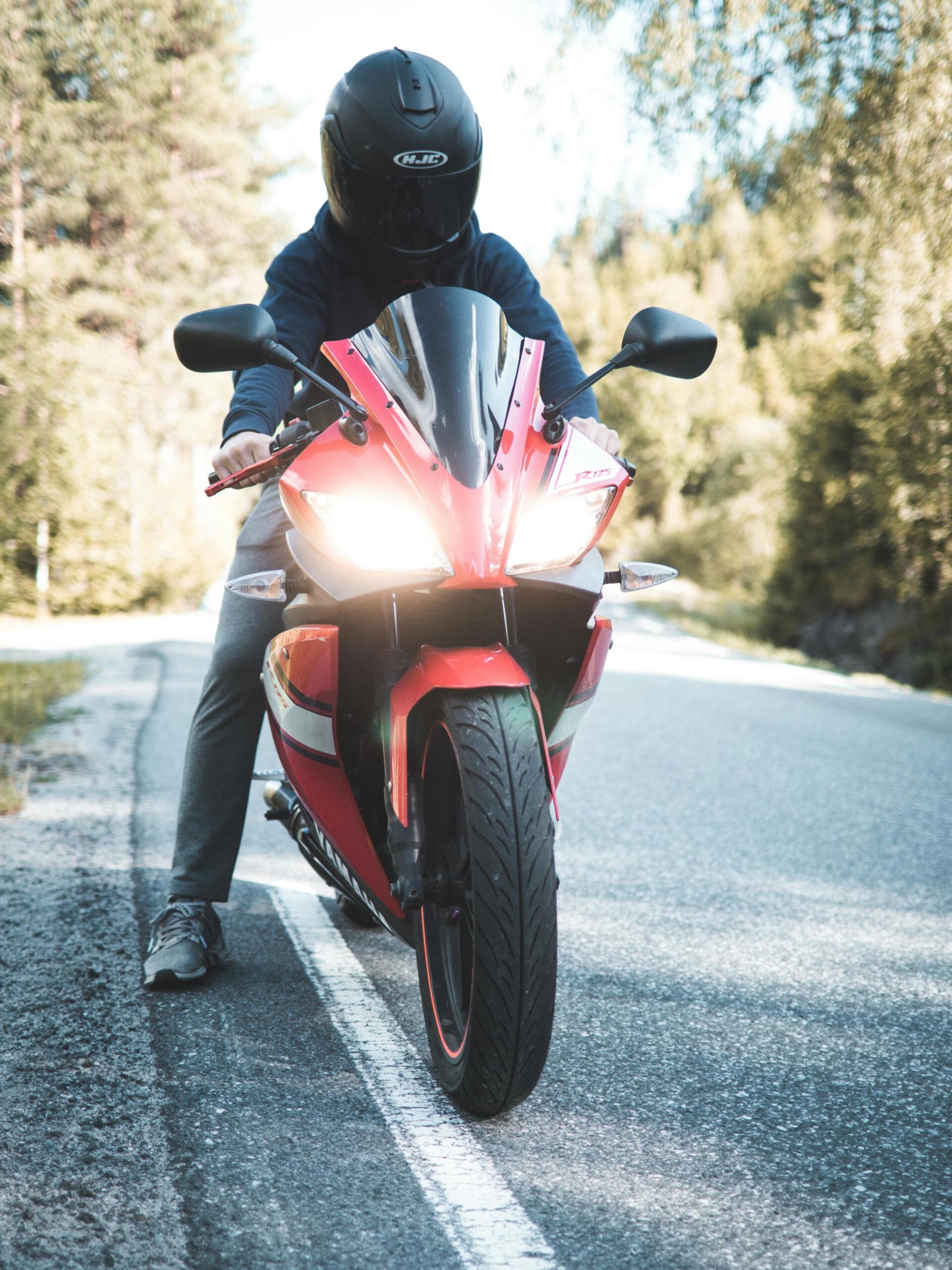 Motorcyclist riding a red sports bike on a city street.