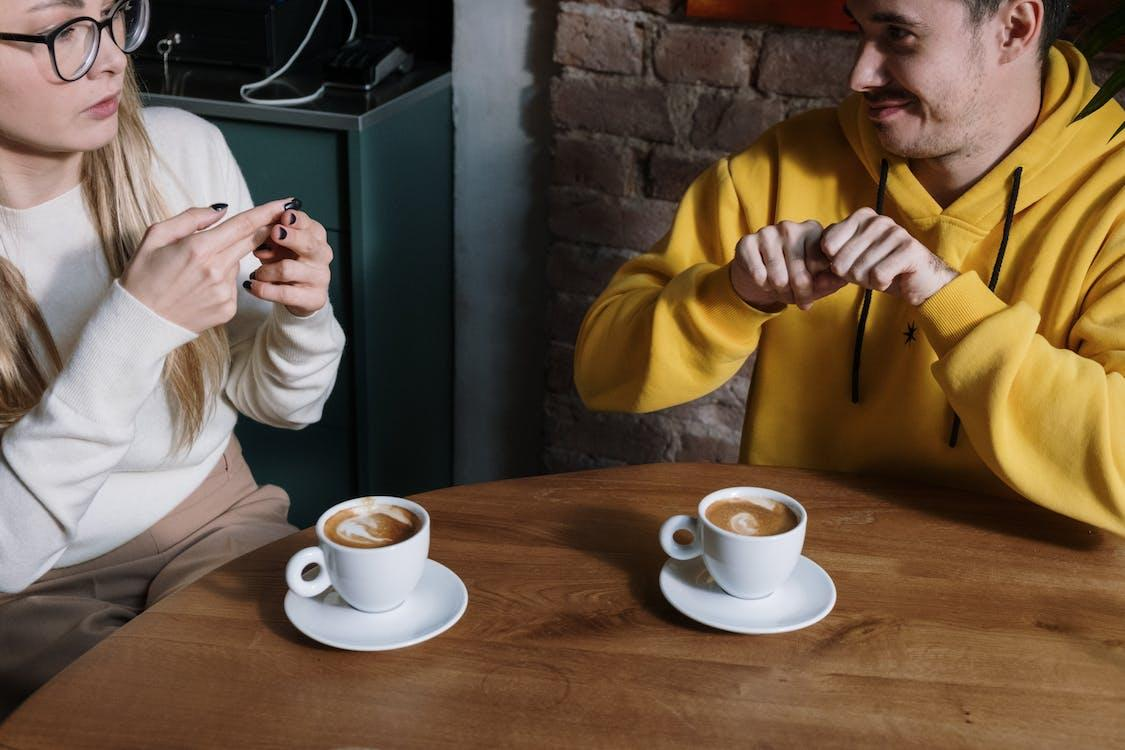 Two people having coffee and communicating in sign language.
