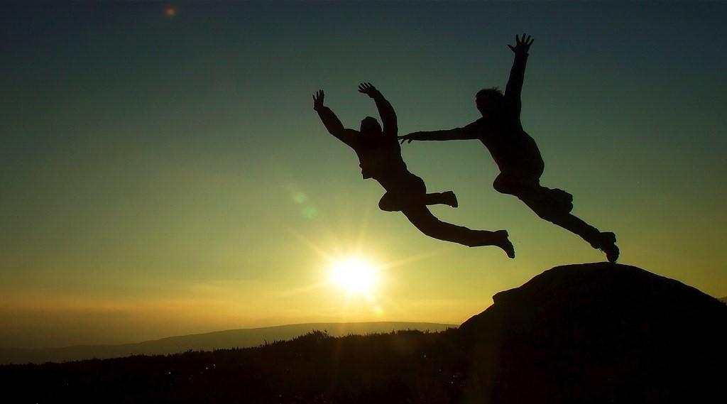Two people jumping off a cliff