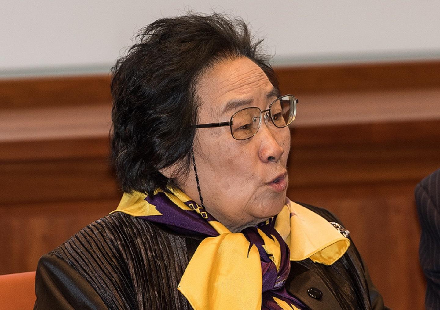 A woman wearing black with a bright yellow scarf.