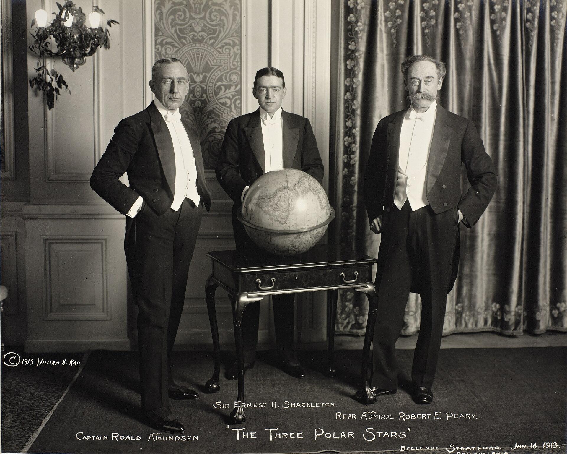 Three men in suits posing around a globe. 