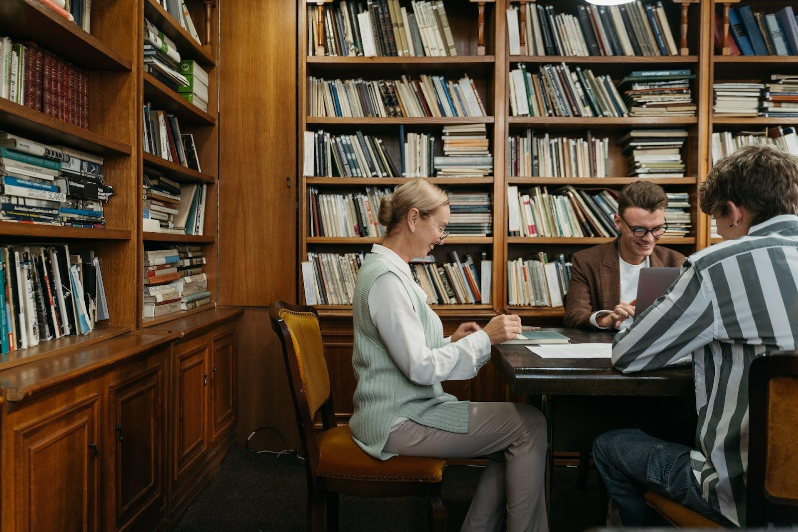People quietly working in a library, each focused on their tasks. The environment is calm, with everyone concentrating on their work, creating a quiet and productive atmosphere.