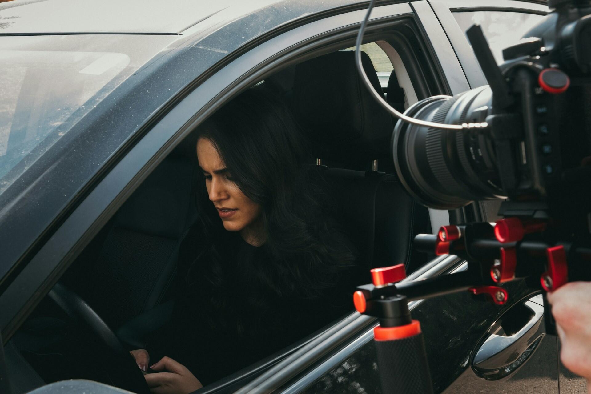 An actress being filmed in a car.