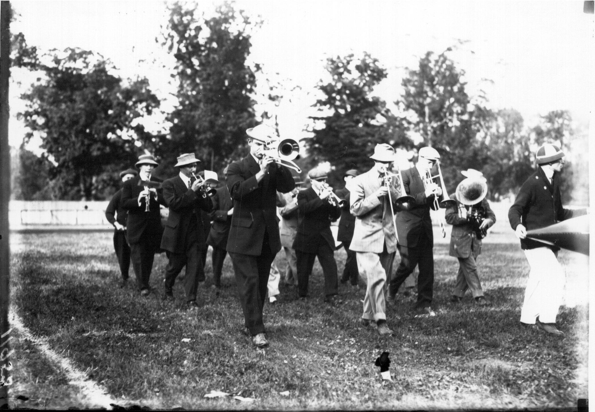 black and white photo of small marching band on football field wearing suits instead of uniforms