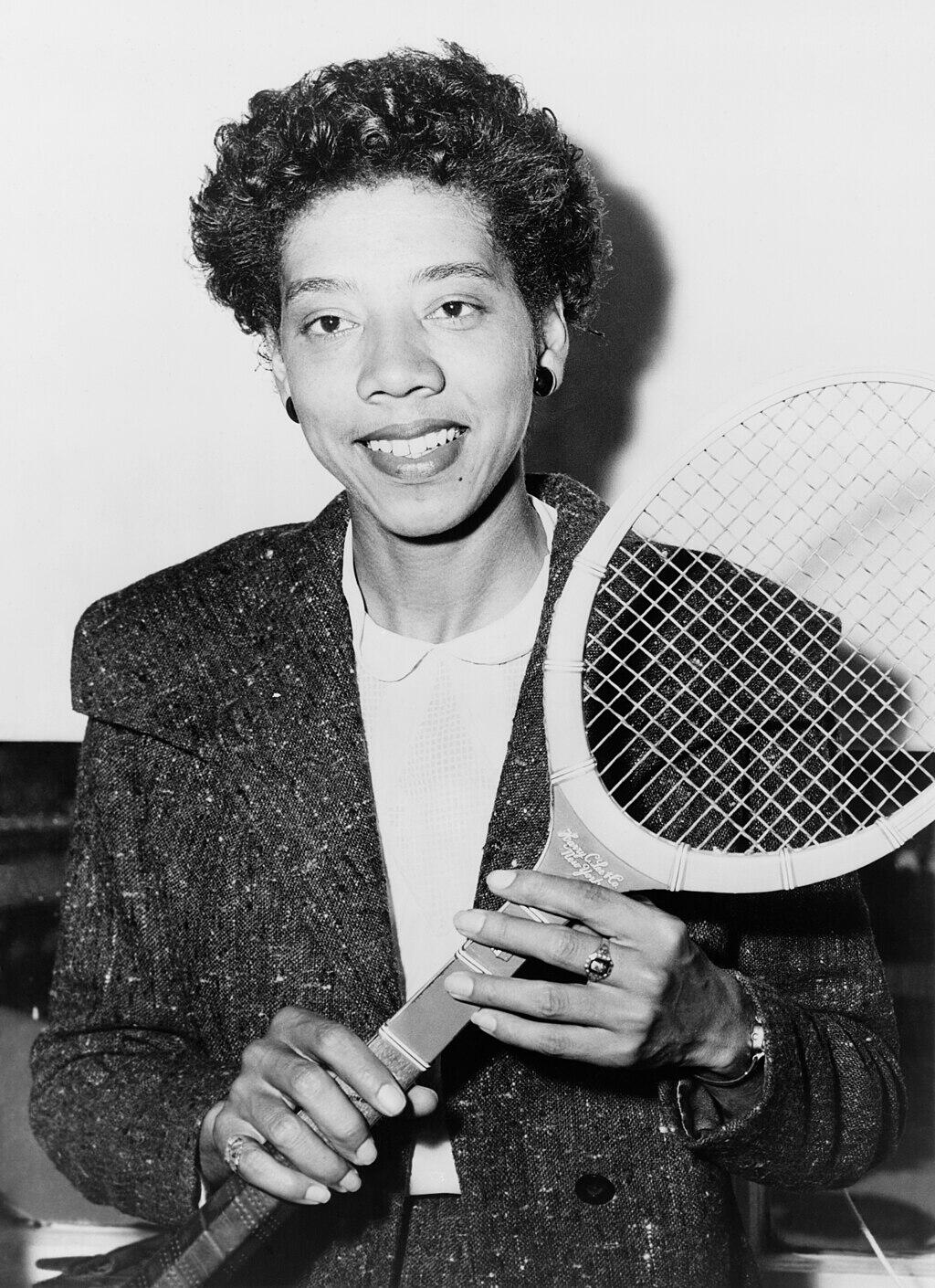 black and white photo of Gibson holding a tennis racket in 1956