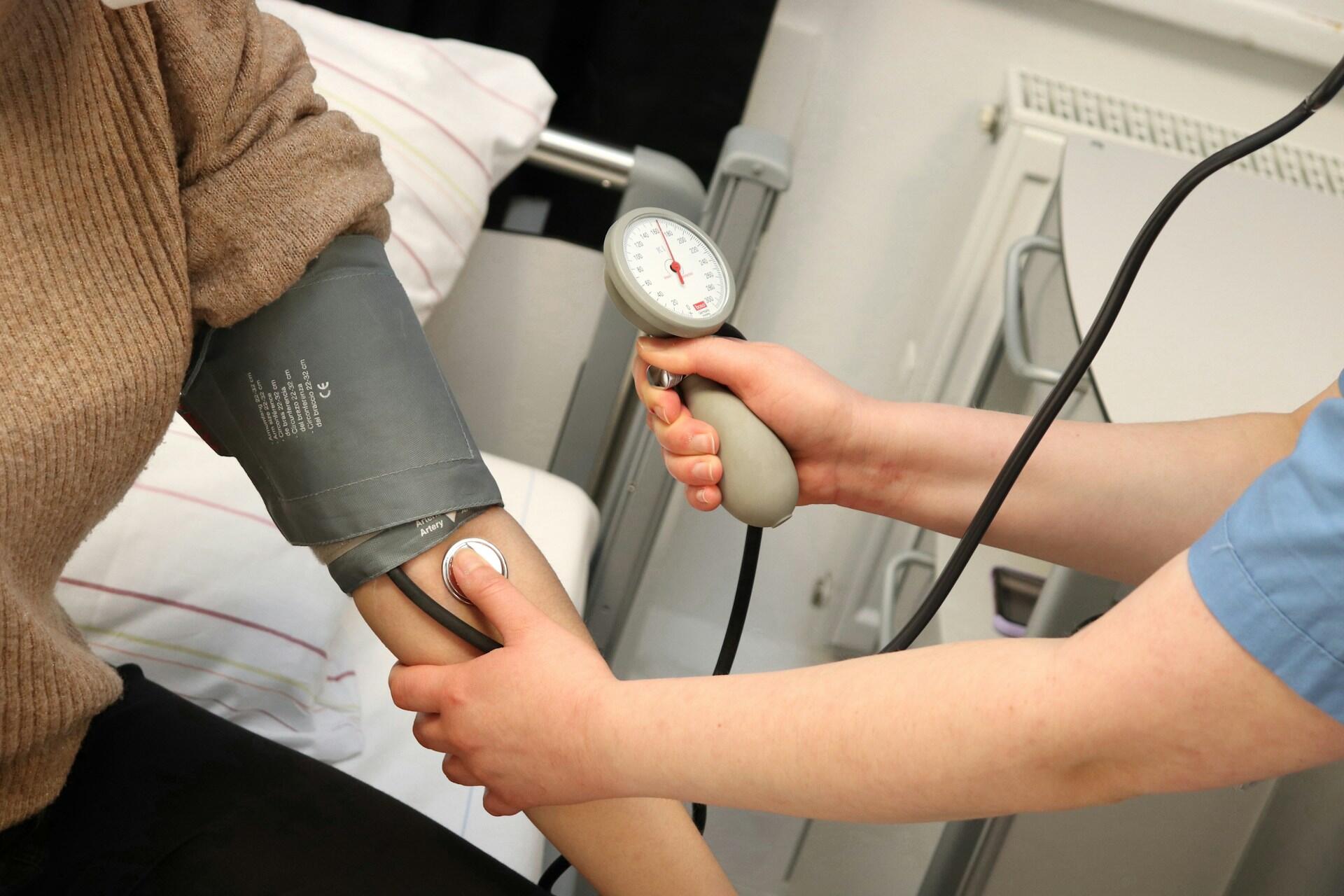 A person taking somebody's blood pressure.
