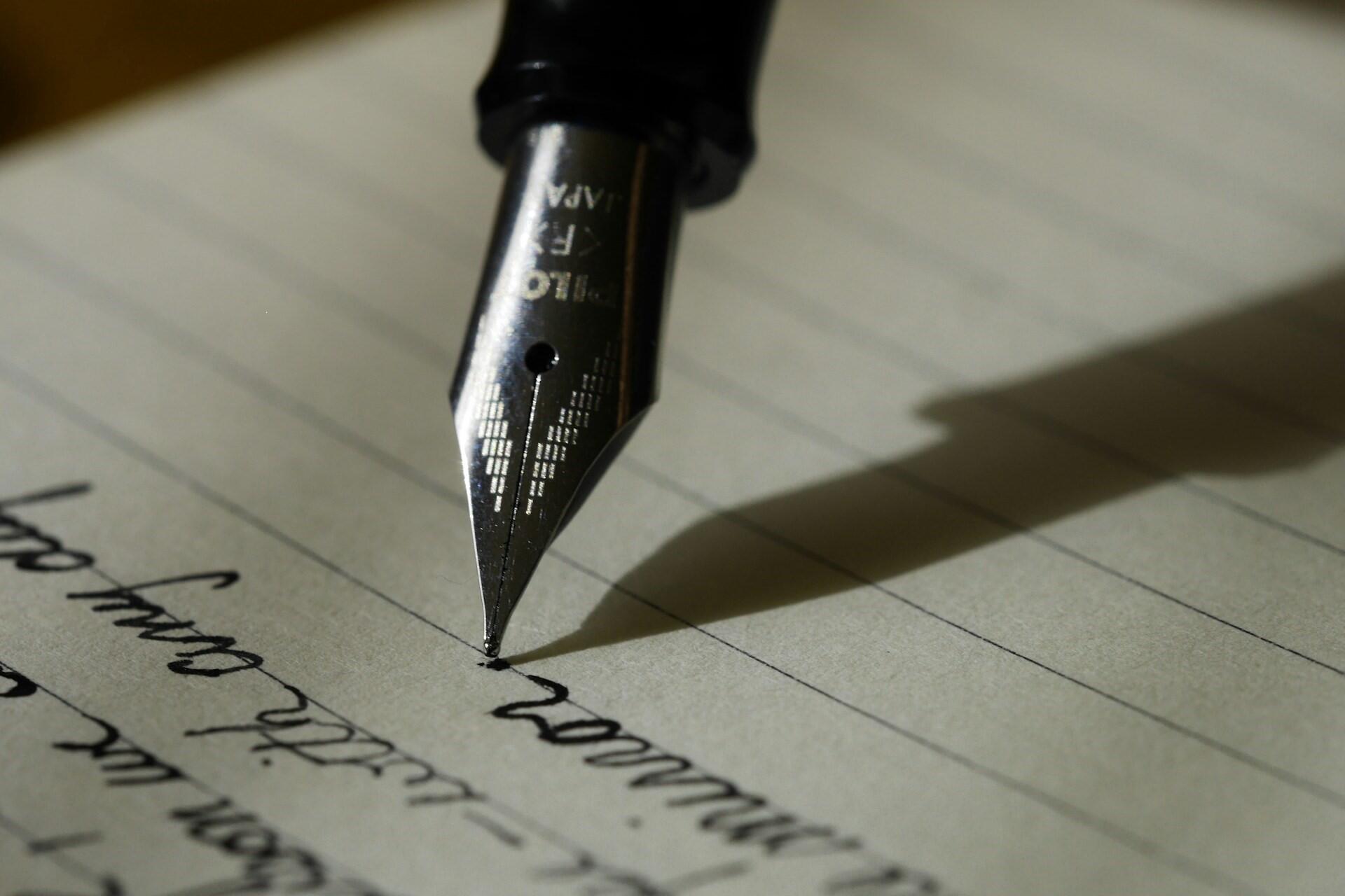 A fountain pen writing on lined paper.