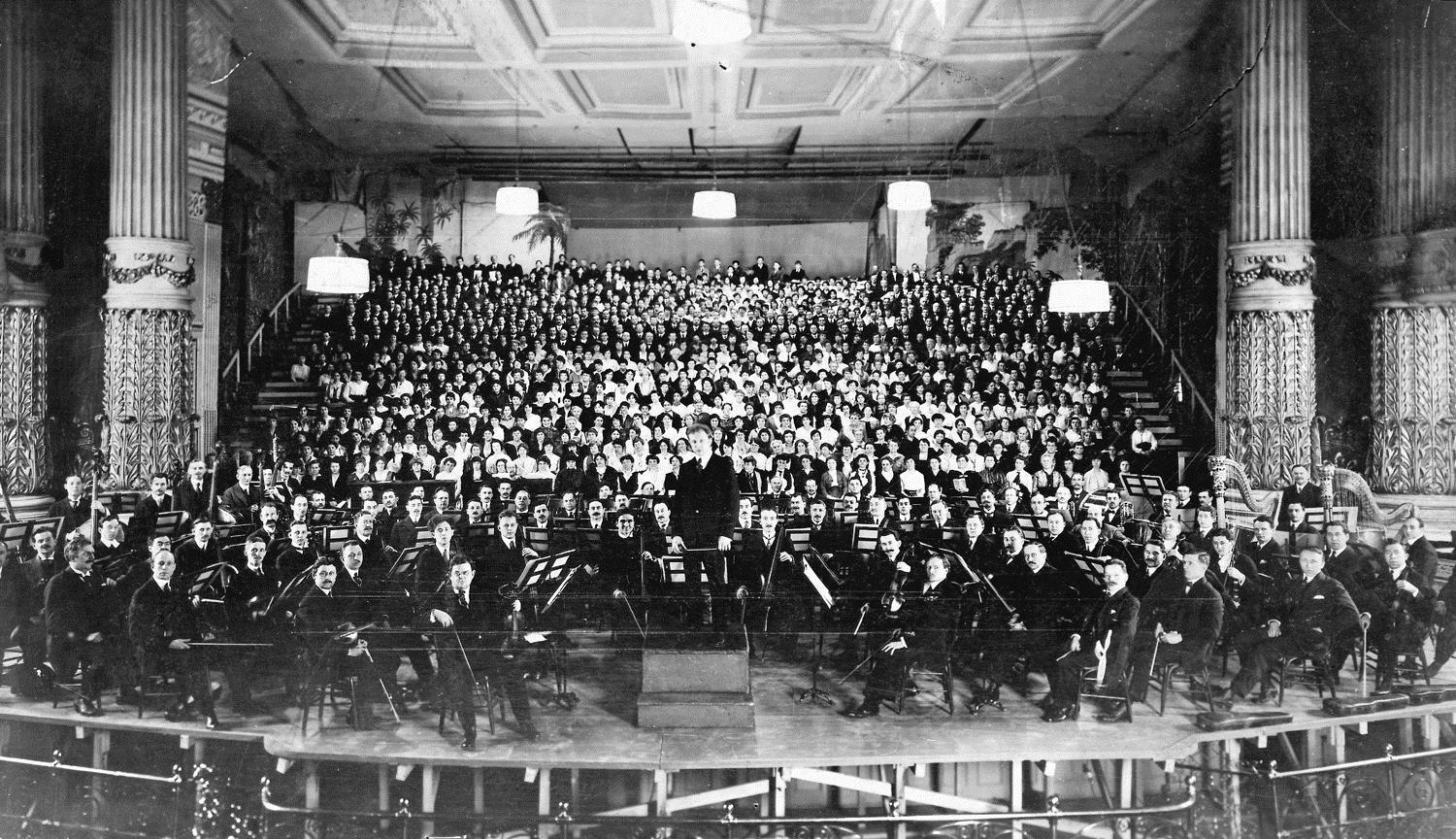 black and white photo of the orchestra on stage with Stokowski at the conductor's stand
