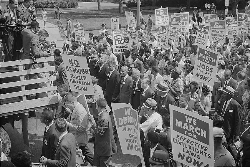 civil rights leaders, including Martin Luther King, Jr., surrounded by crowds carrying signs, 1963