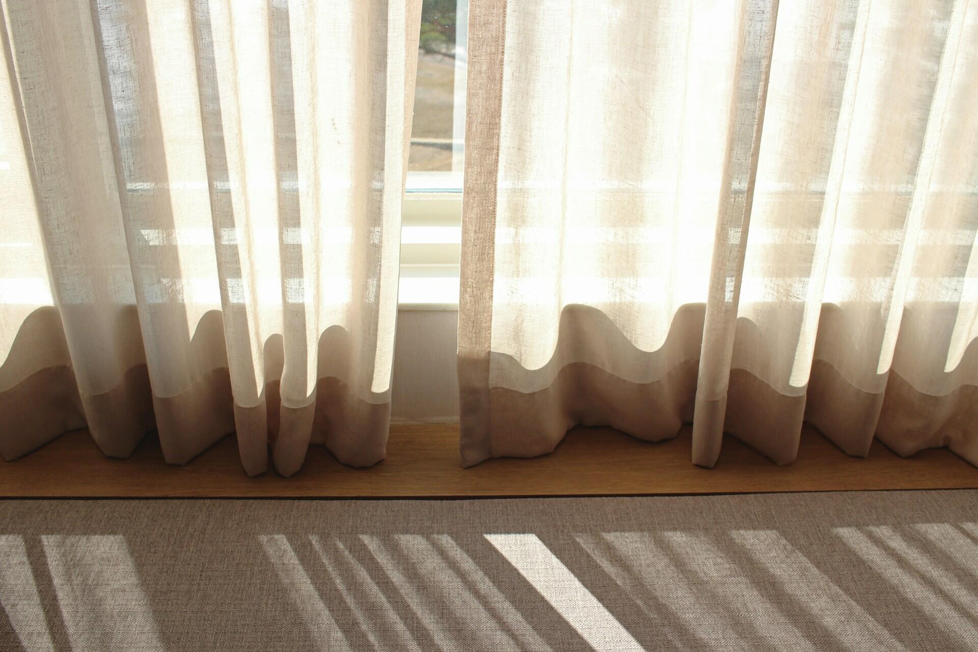 Well hemmed curtains above a windowsill. 
