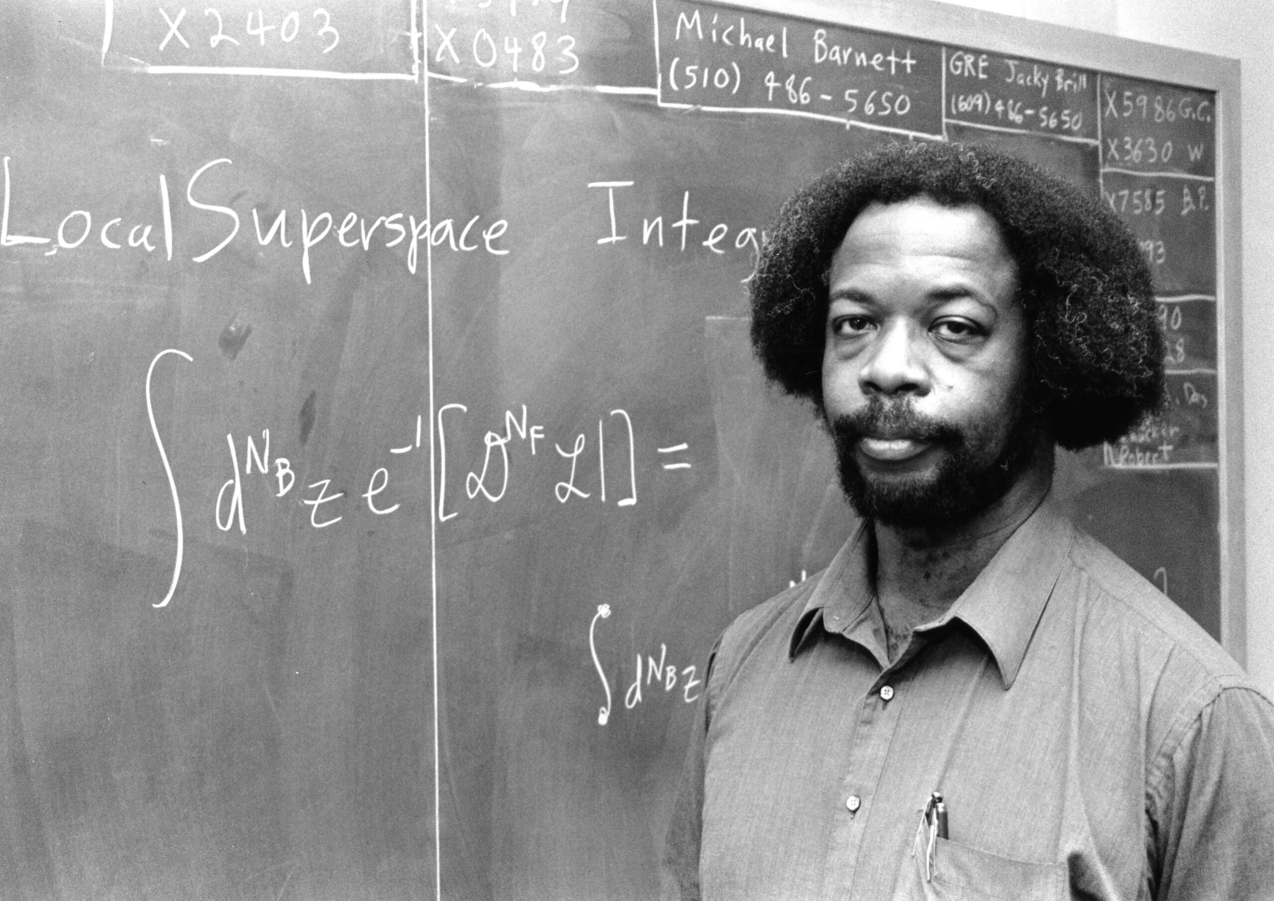 Gates giving a lecture in front of a chalkboard.