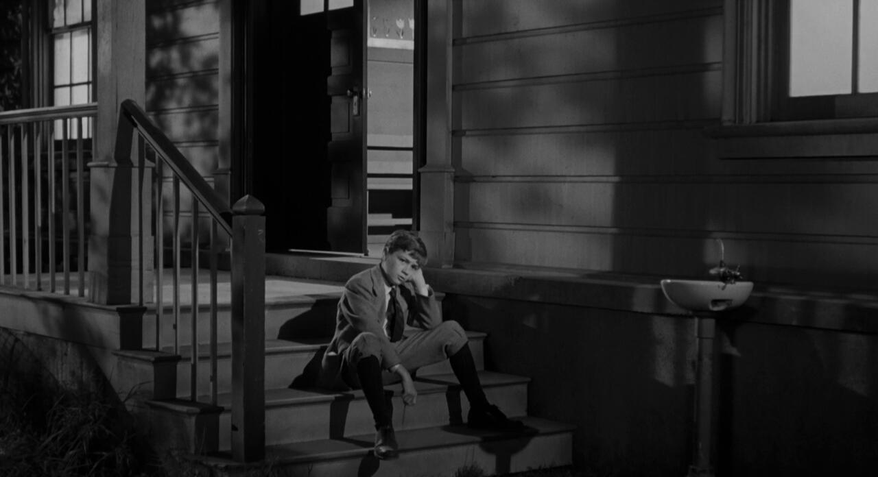 Jem sitting on the porch steps in the 1962 film