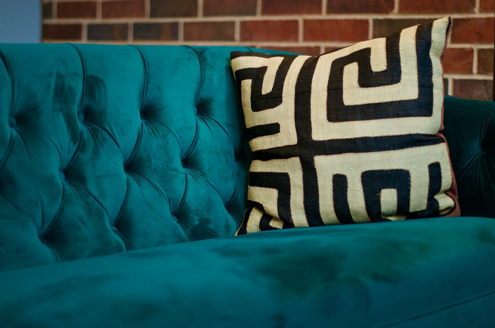 a tan and black pillow on a turquoise sofa. 