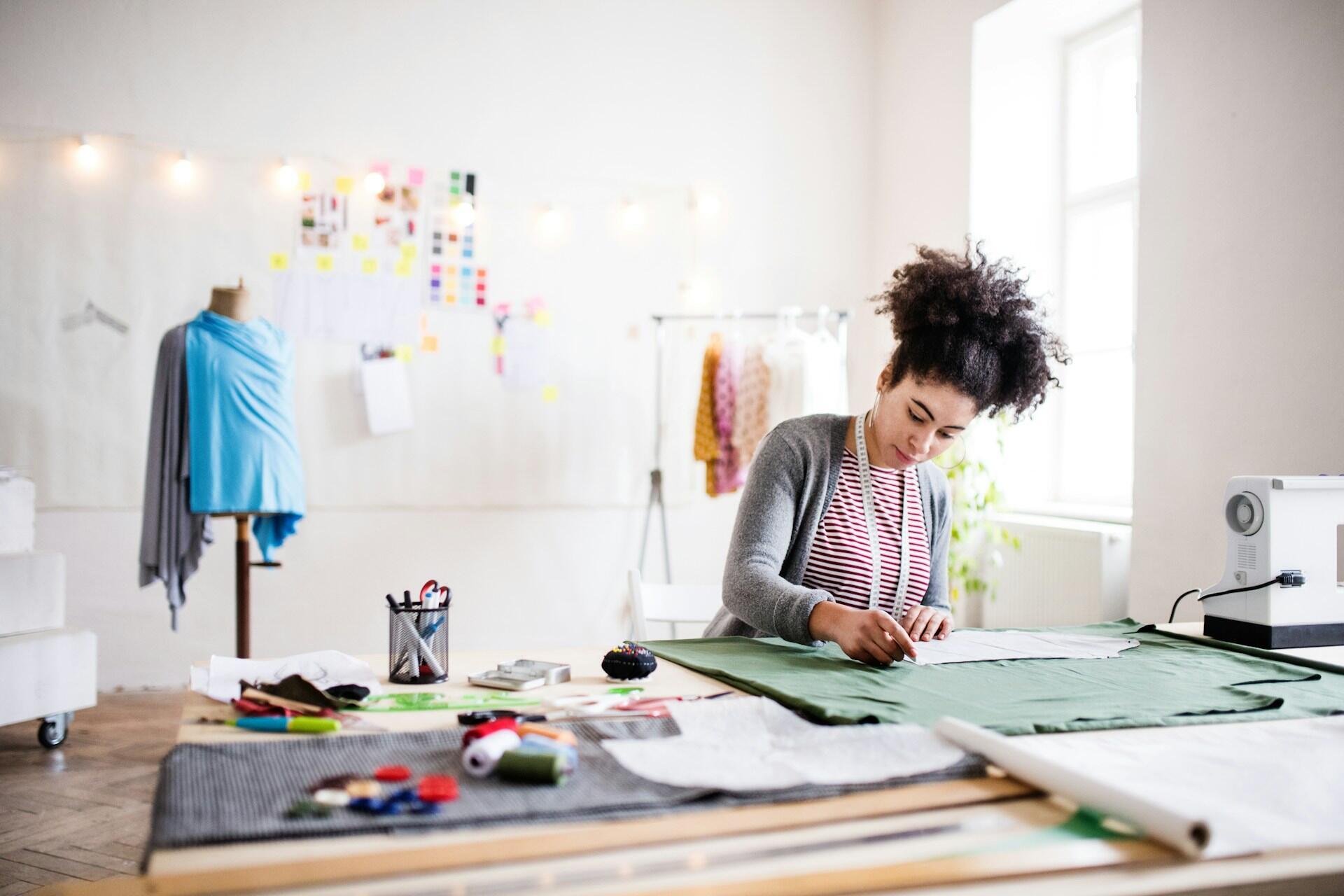 A woman at a sewing table, working. 