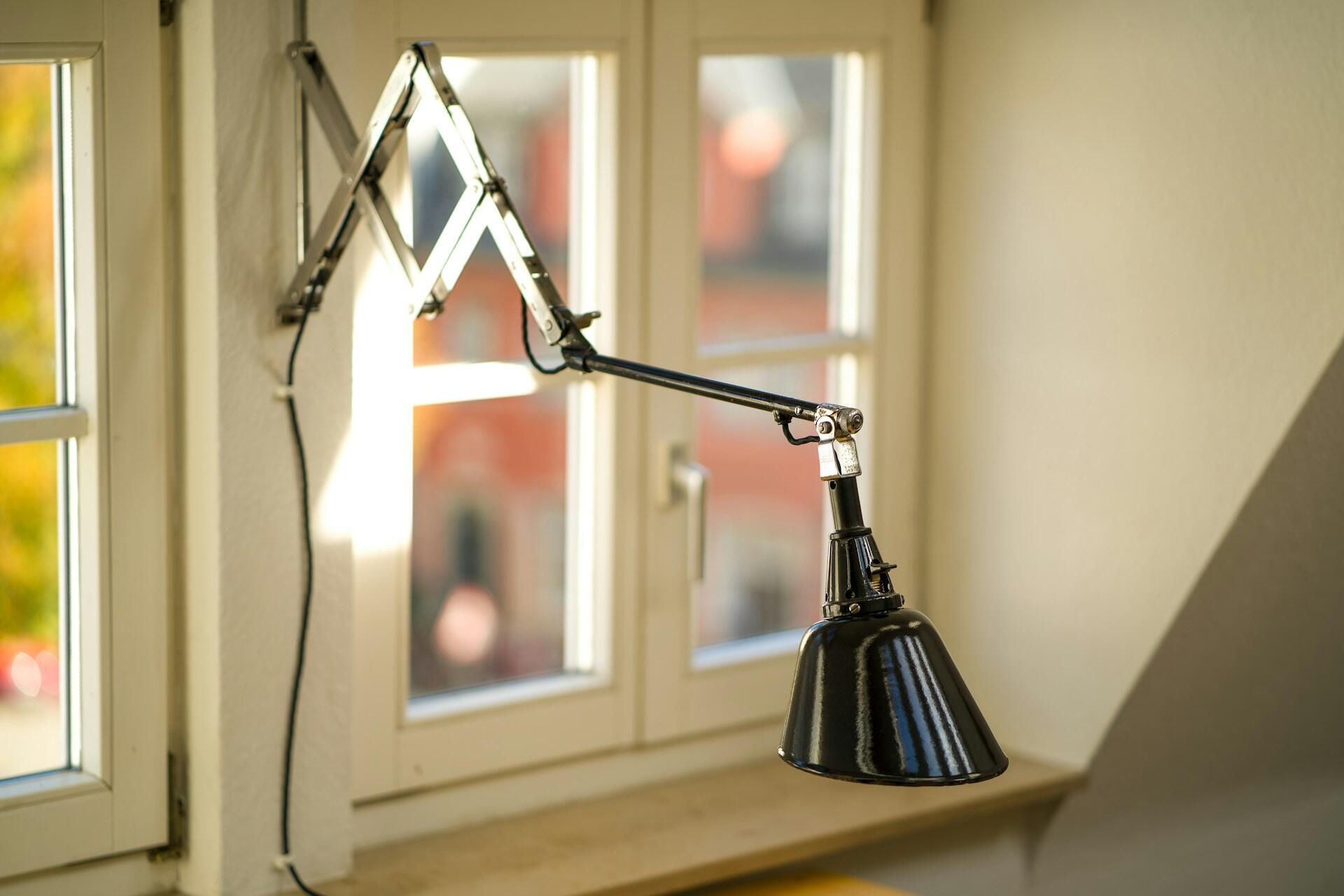 A black lamp mounted between two windows. 