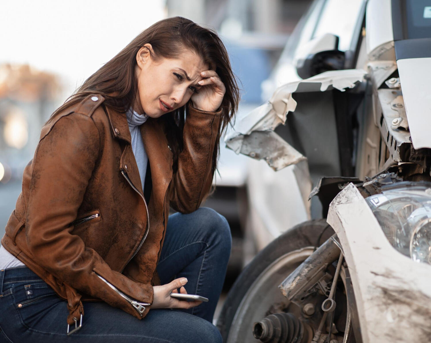 young driver looking at damage to car, devastated expression