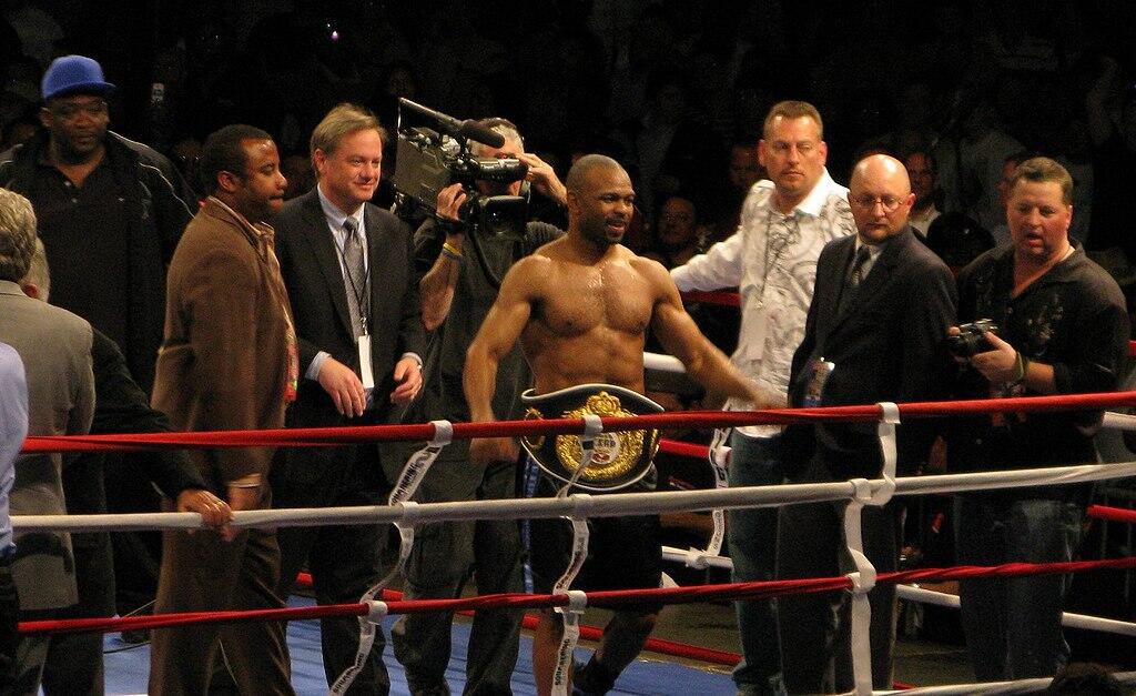 Jones wearing a boxing belt, celebrating his win in a boxing ring.