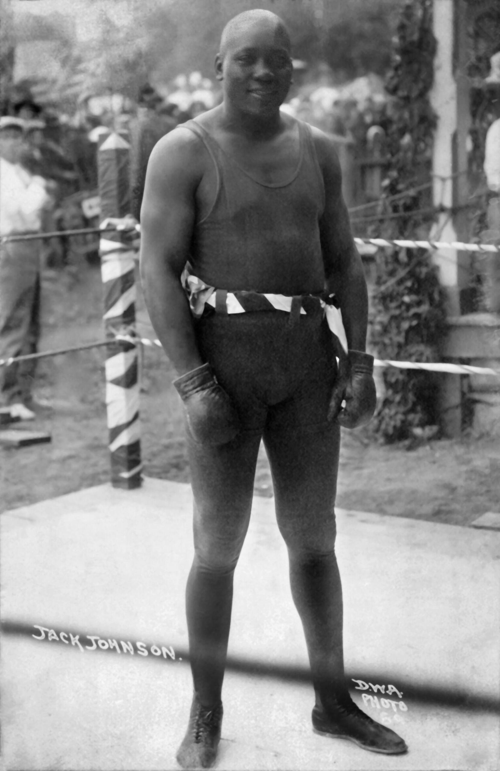 Old black and white photo of Jack Johnson standing in a boxing ring.