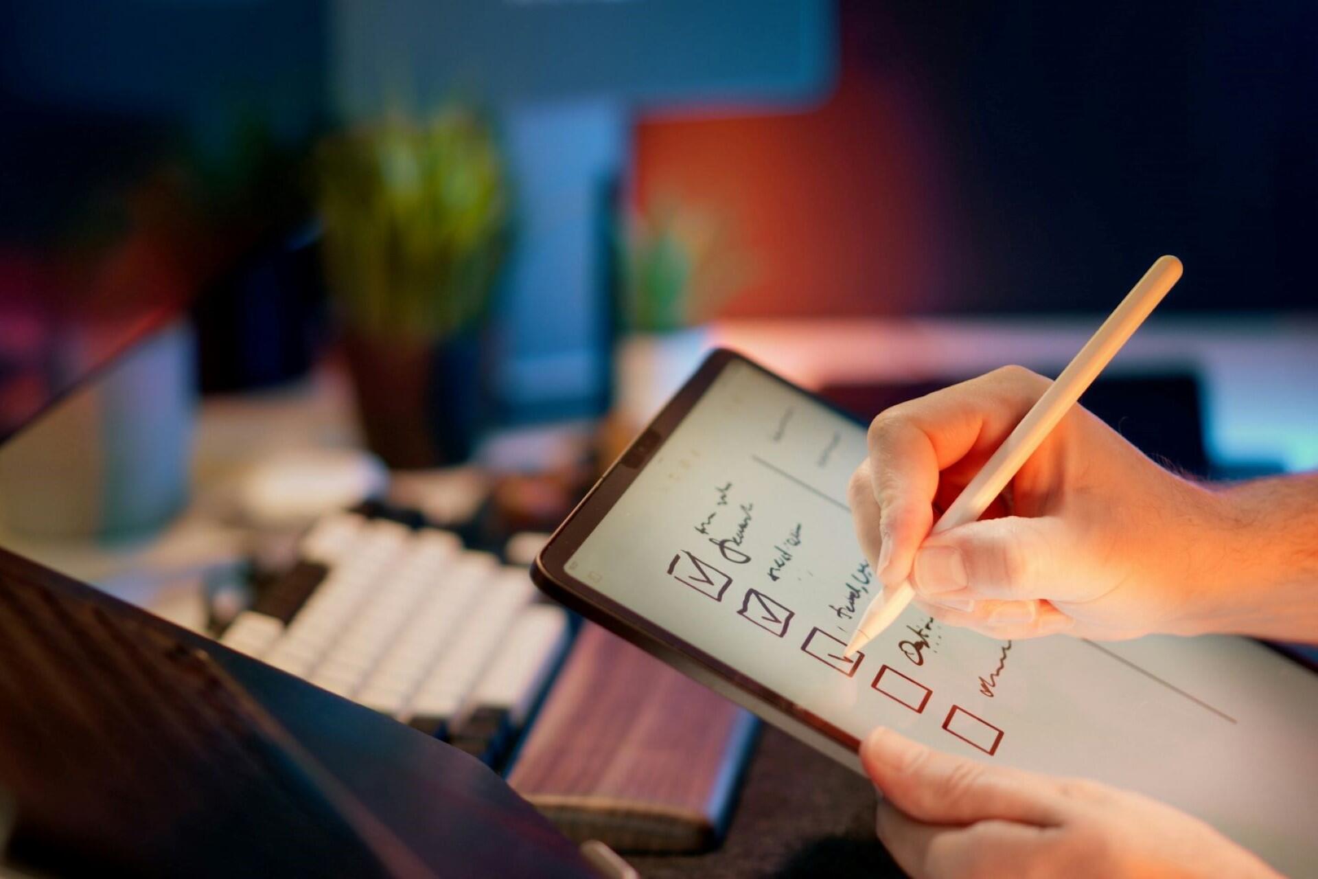 Hand using a stylus to tick off tasks on a digital checklist displayed on a tablet.