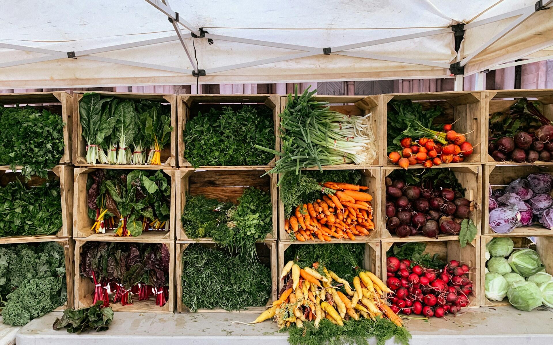 Wooden crates filled with fresh vegetables displayed at a market stall.