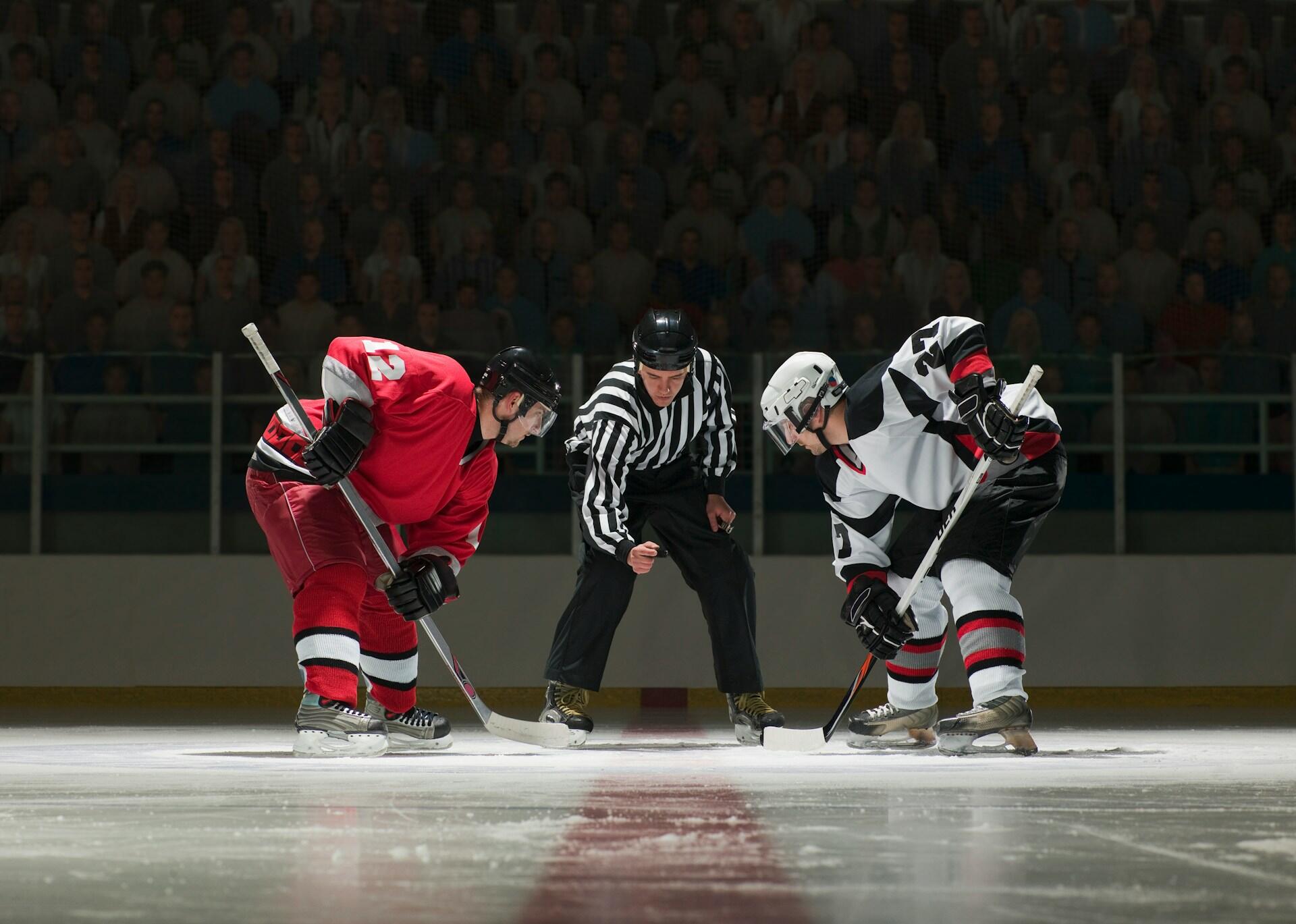 Two hockey players when the referee drops the puck to start the game.