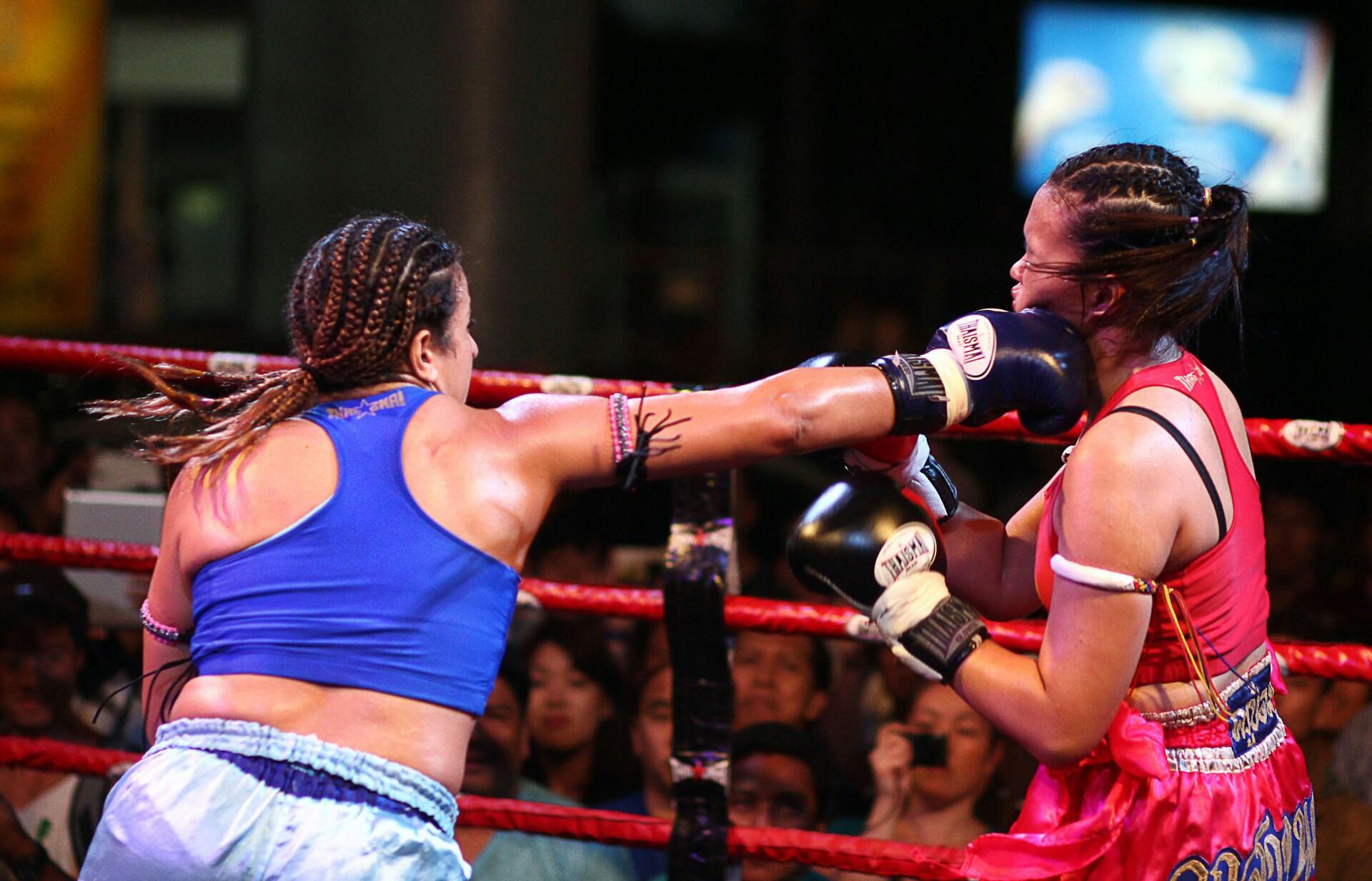 A women in blue punching another boxer wearing red inside the ring?