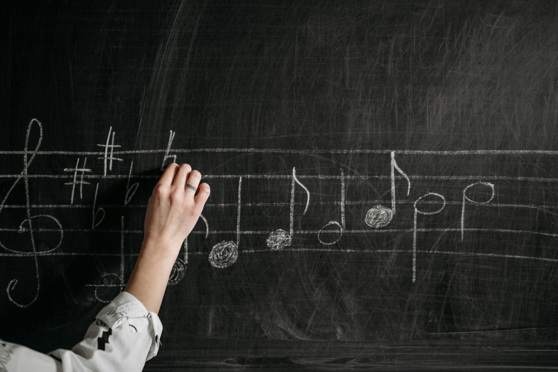 teacher writing music notes on a chalkboard for a lesson
