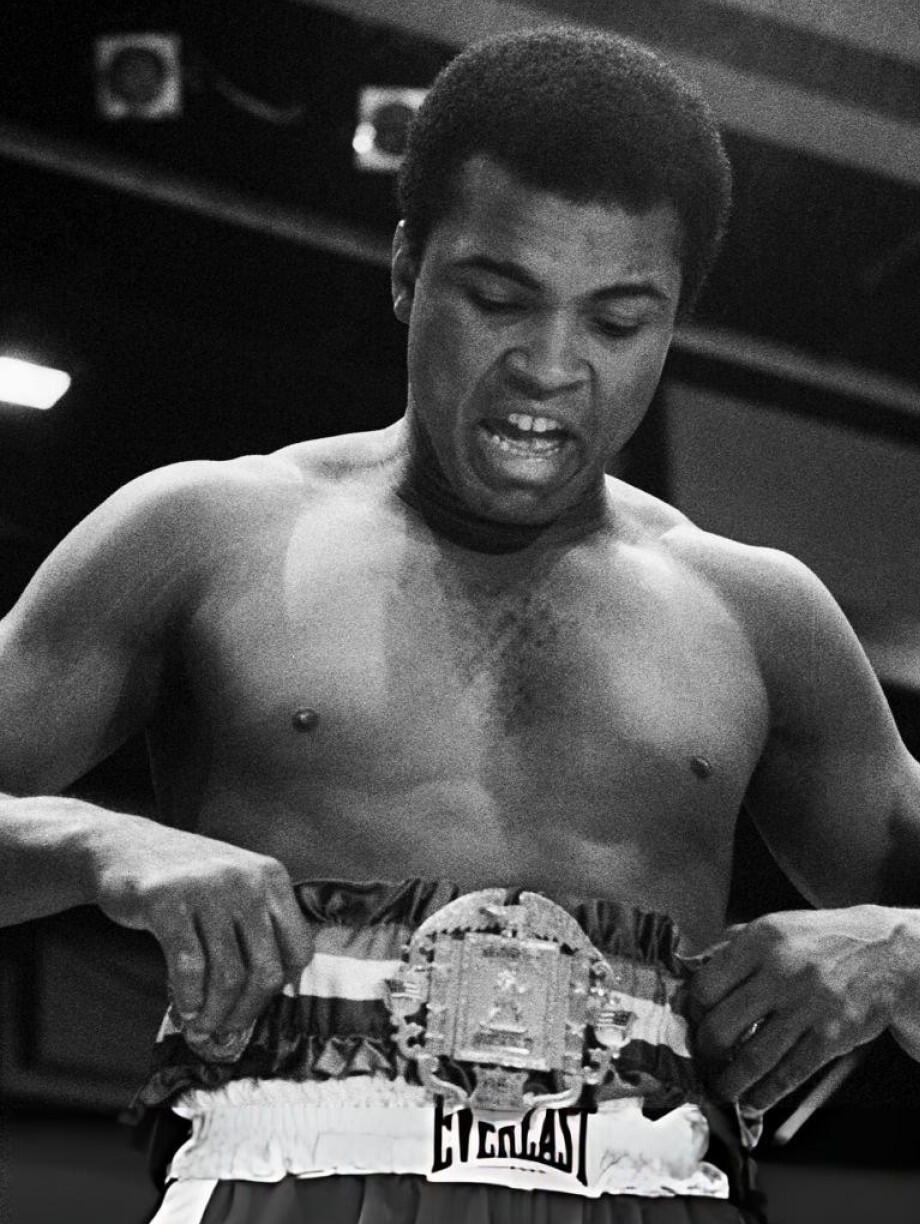 Muhammad Ali strapping on boxing belt.
