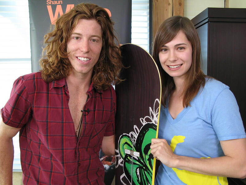 Shaun White posing next to a fan and a snowboard.