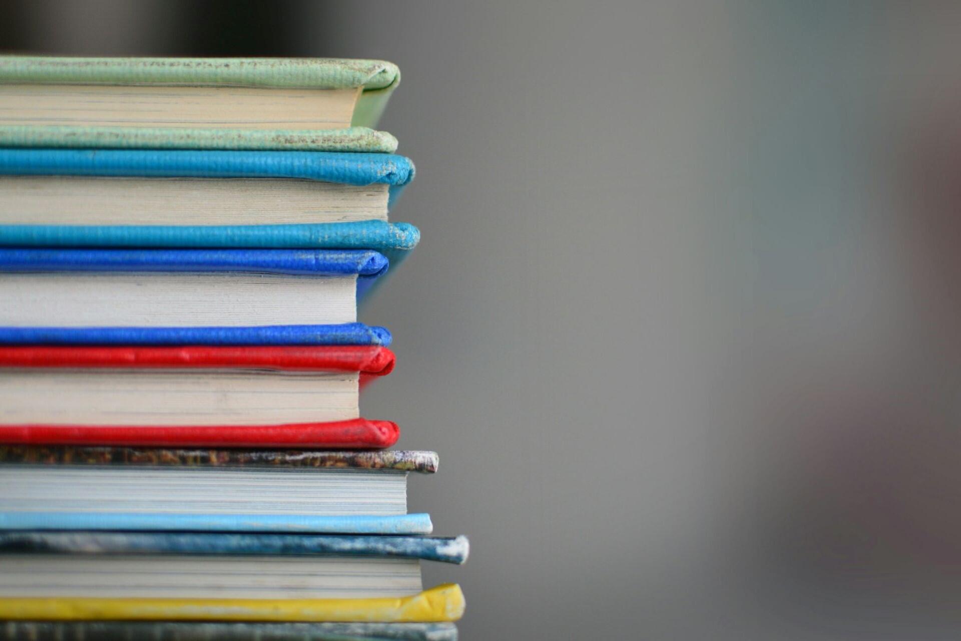 Stack of hardcover books with colourful covers arranged vertically.