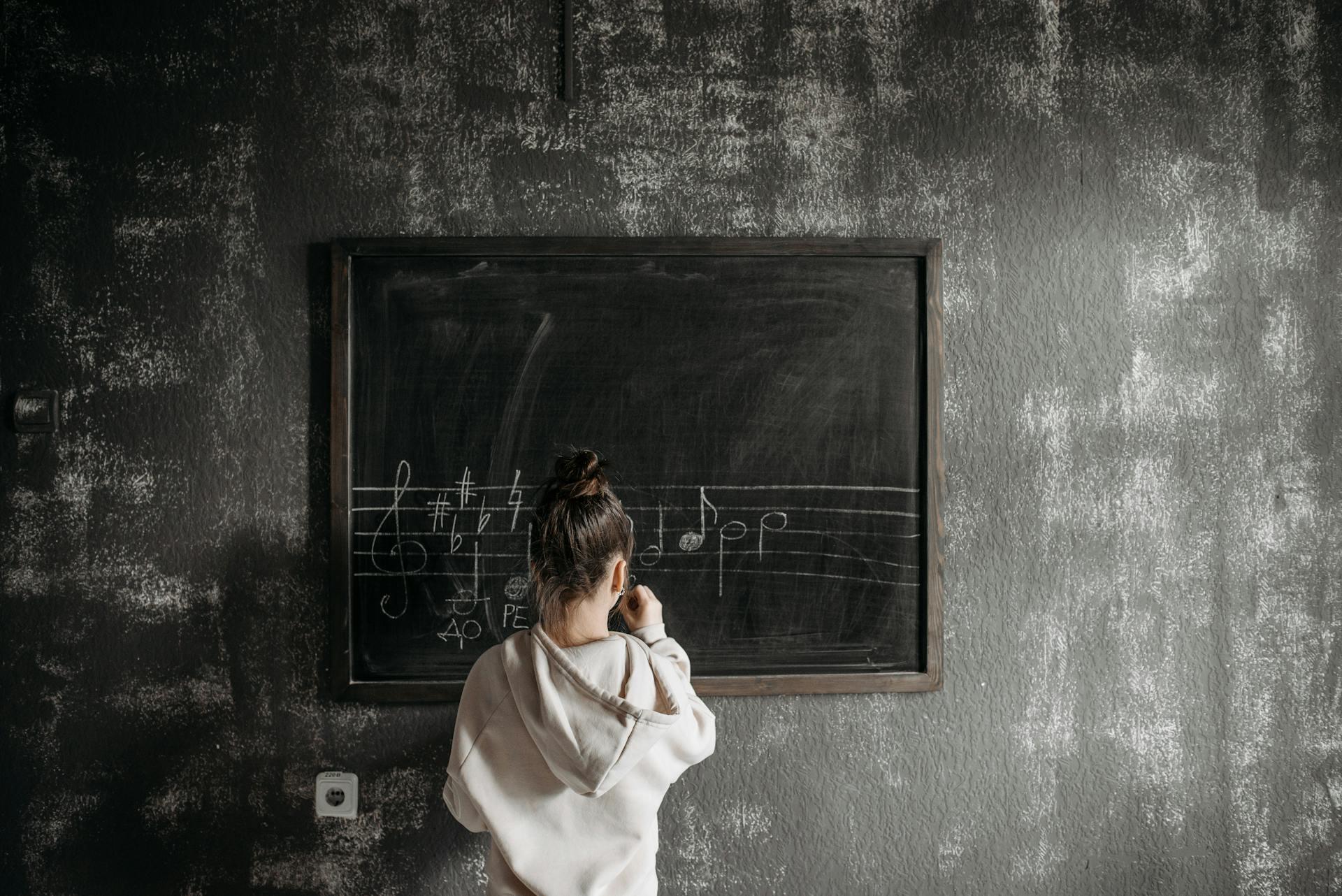 student writing music notes on a chalkboard