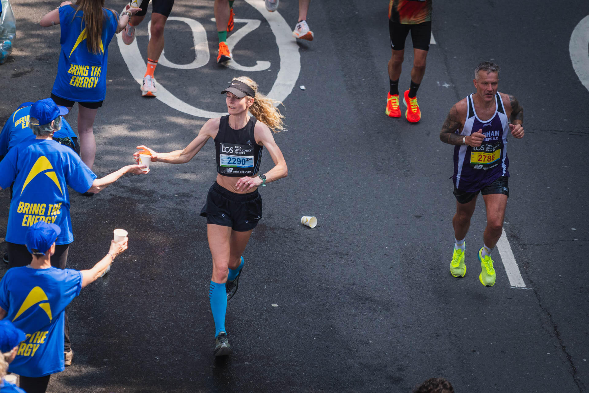 Runner getting a cup from a volunteer handing out drinks