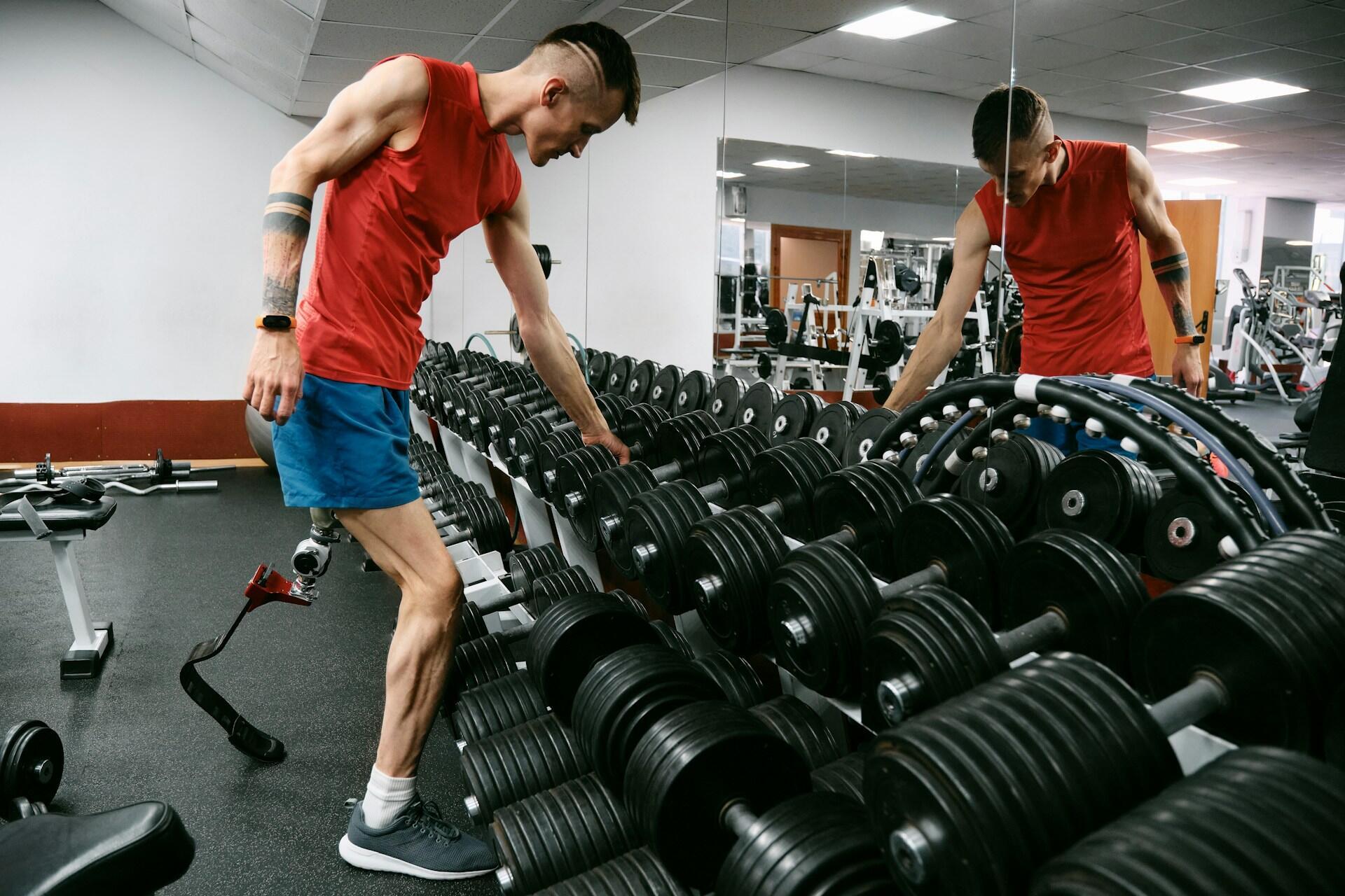 Disabled athlete training in the gym with dumbbells.