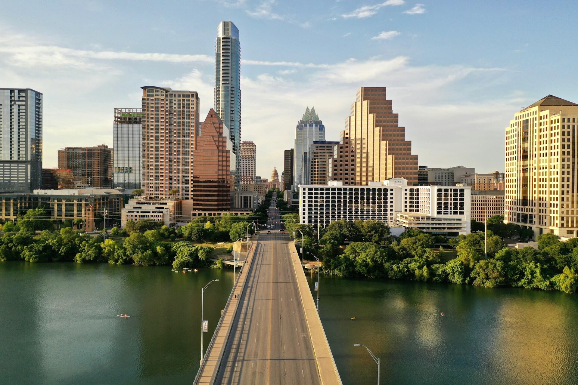 Austin skyline with high-rise buildings, bridge, river, and green parkland