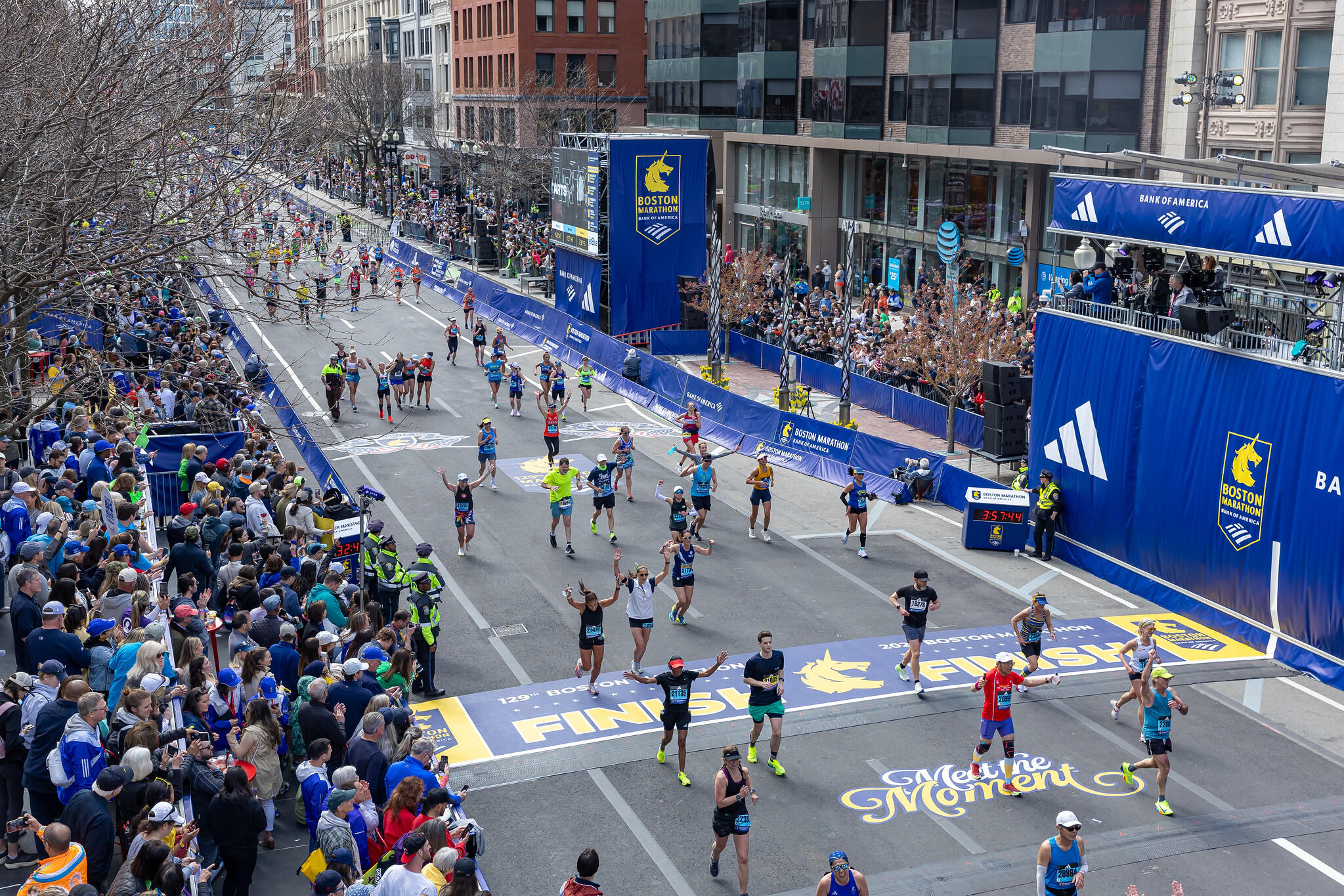 Marathon runners crossing the yellow and blue finish line of the Boston Marathon