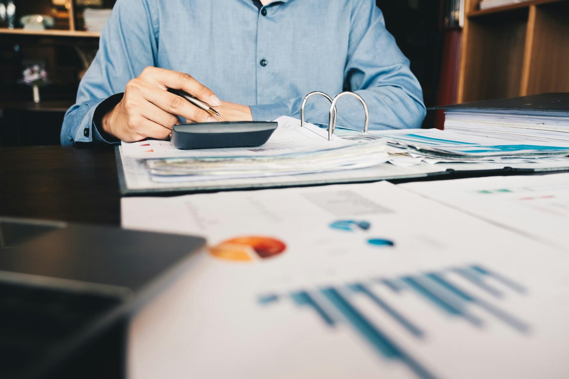 person using a calculator and looking at financial accounting information