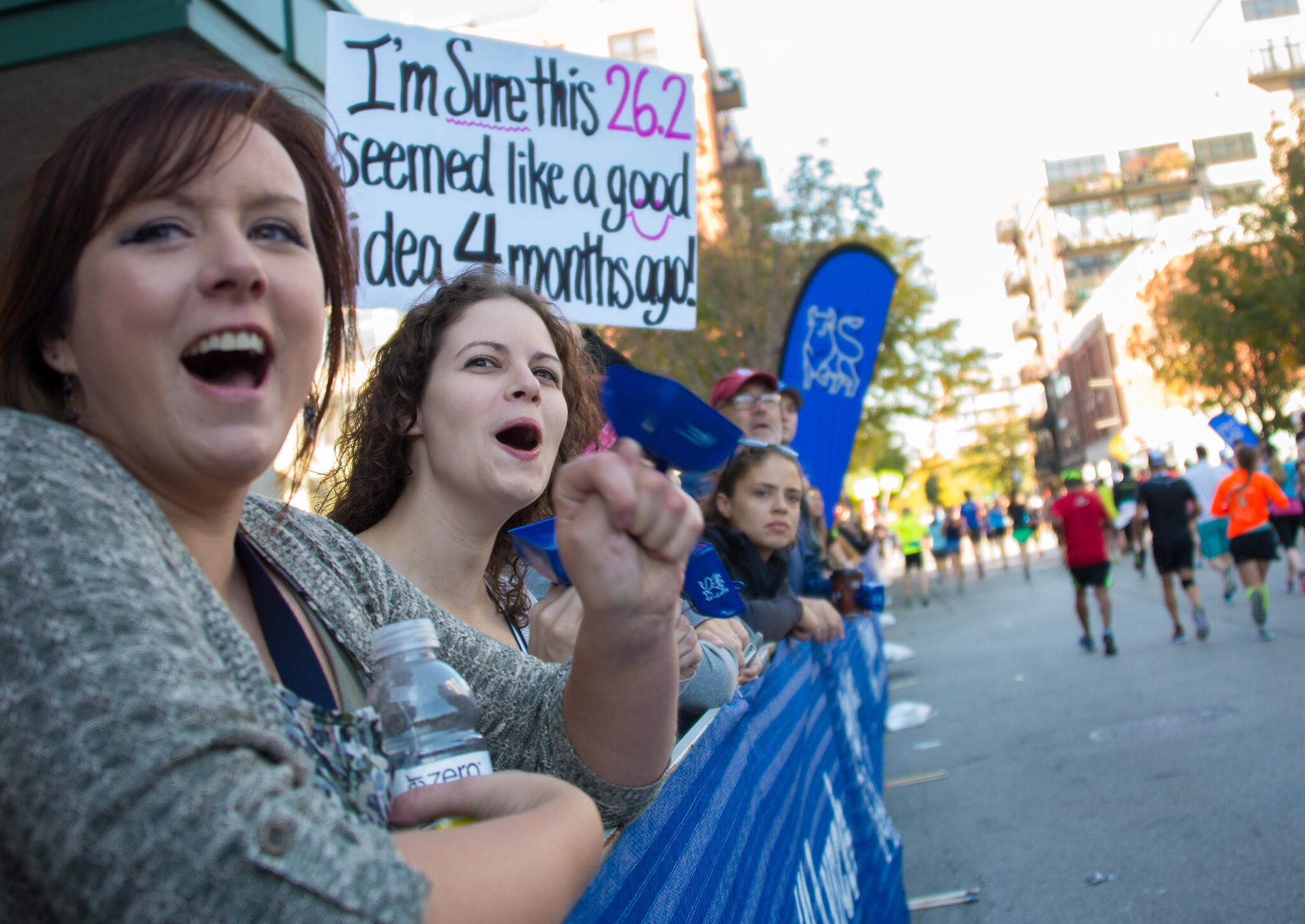spectators cheering on runners with supportive signs