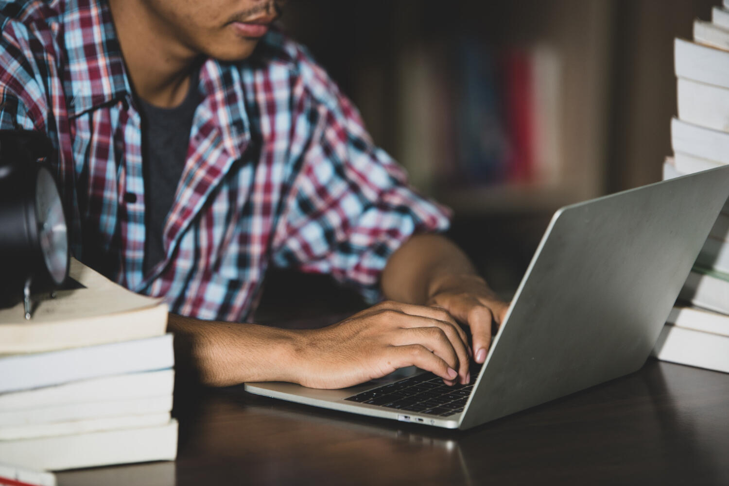 person using a computer with textbooks nearby
