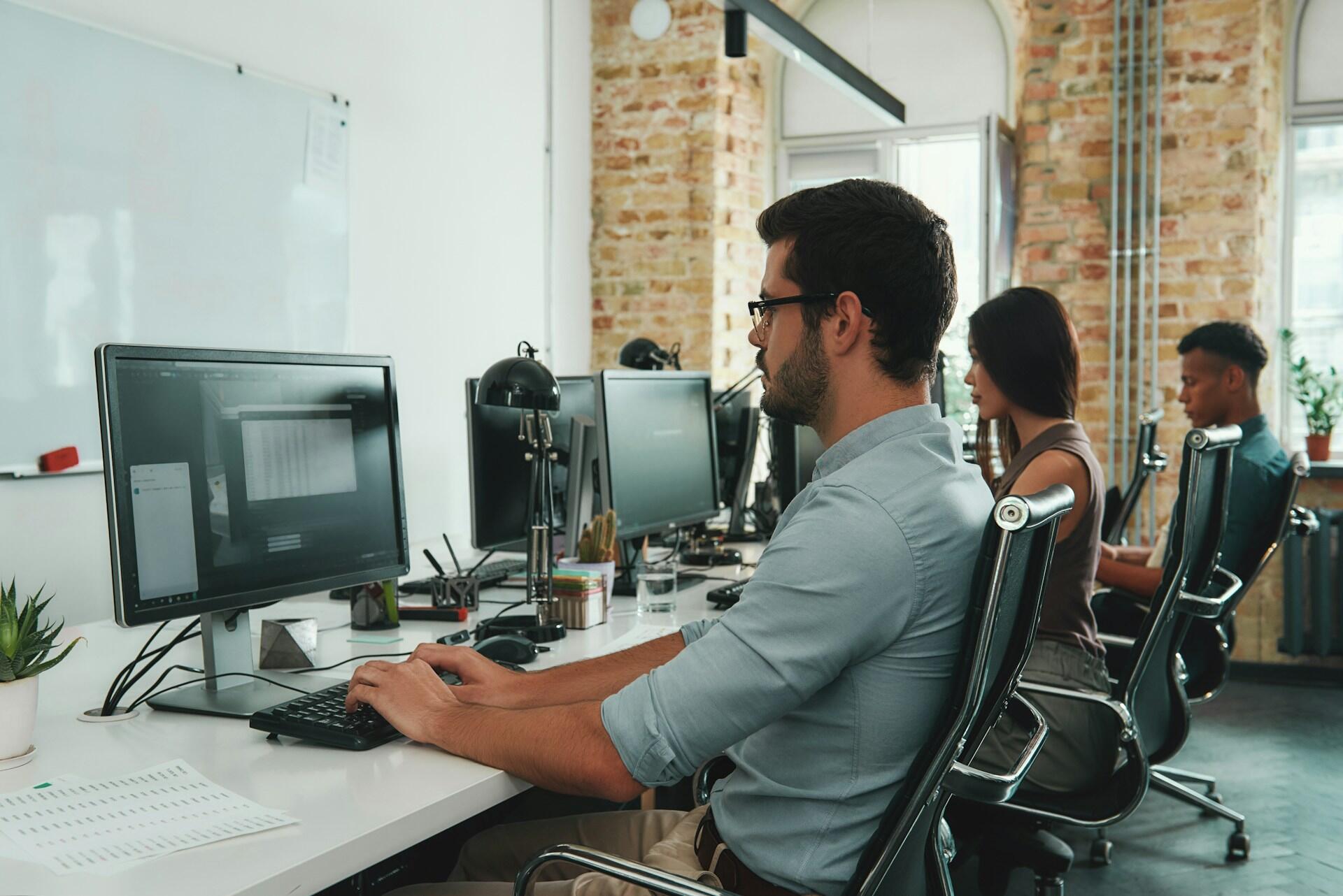 workers in an office with computers and financial data