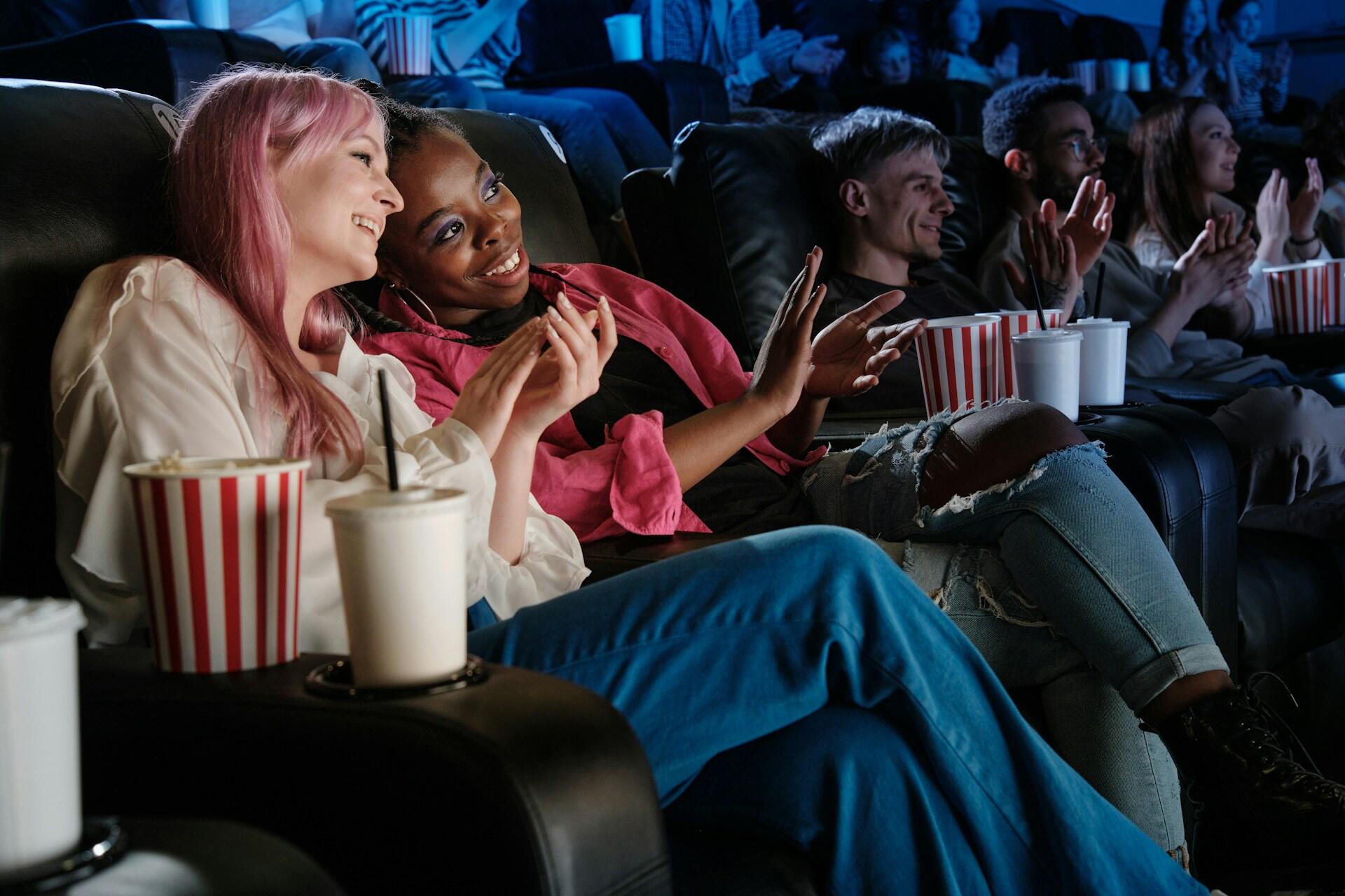 Two girls chatting while watching a movie in a movie theater.