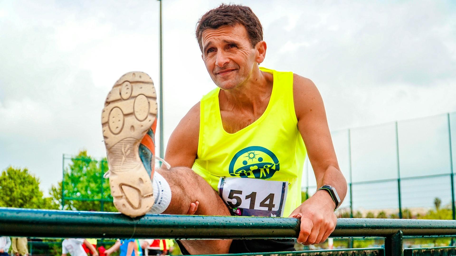a man with a marathon bib stretching his leg
