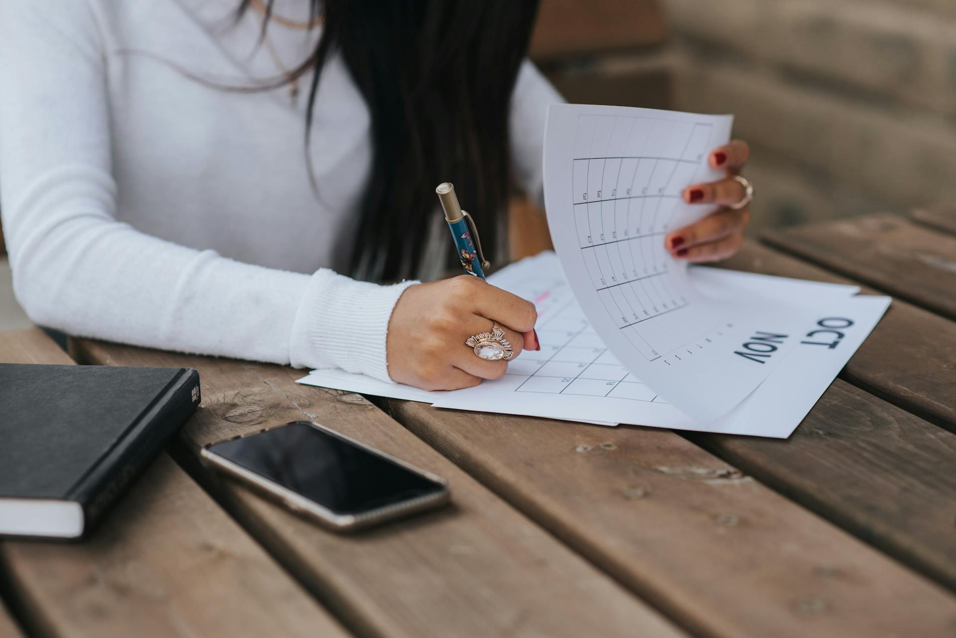 person looking through pages of a calendar and making notes