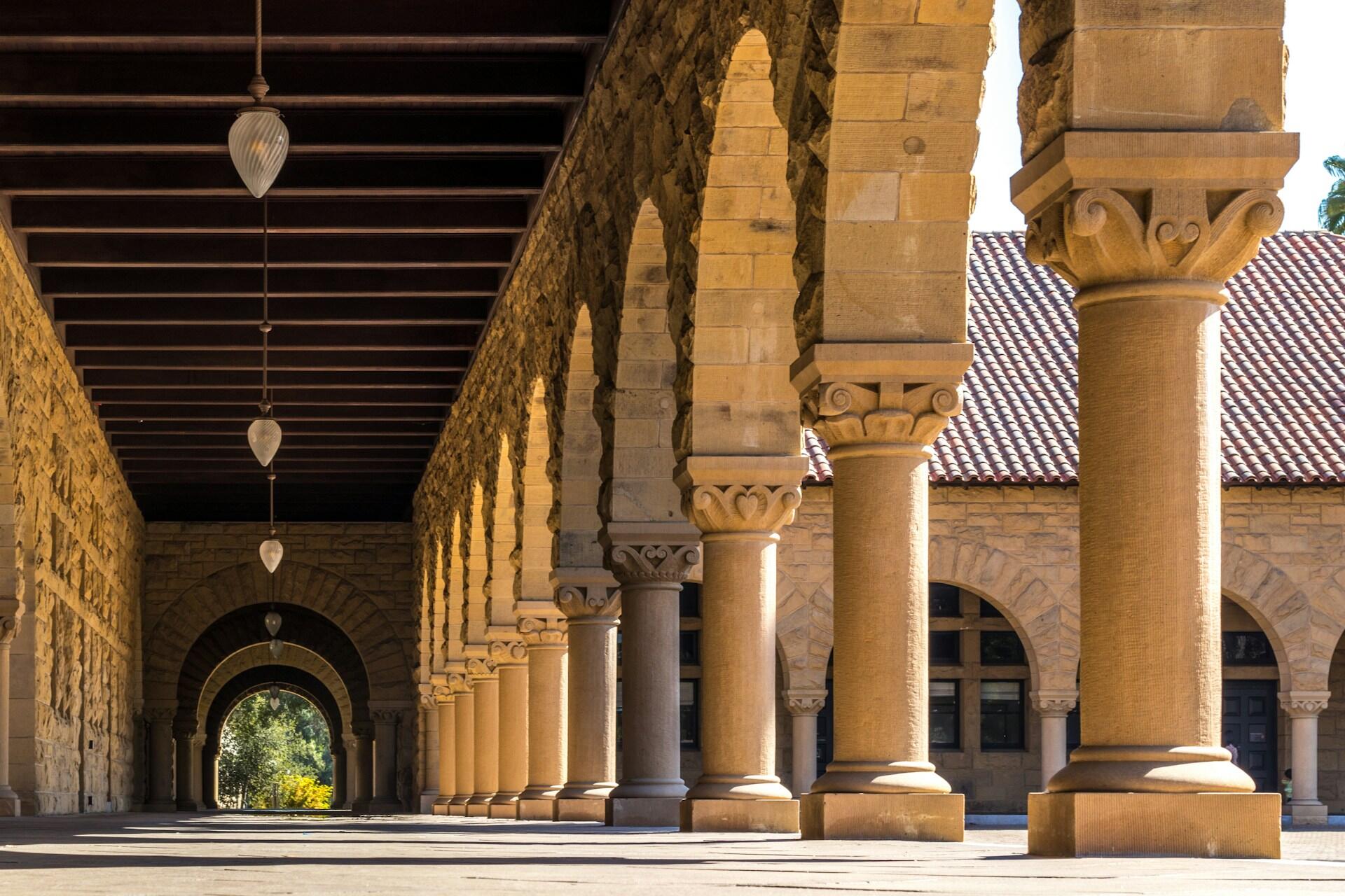 Stone archways and columns along a university courtyard walkway