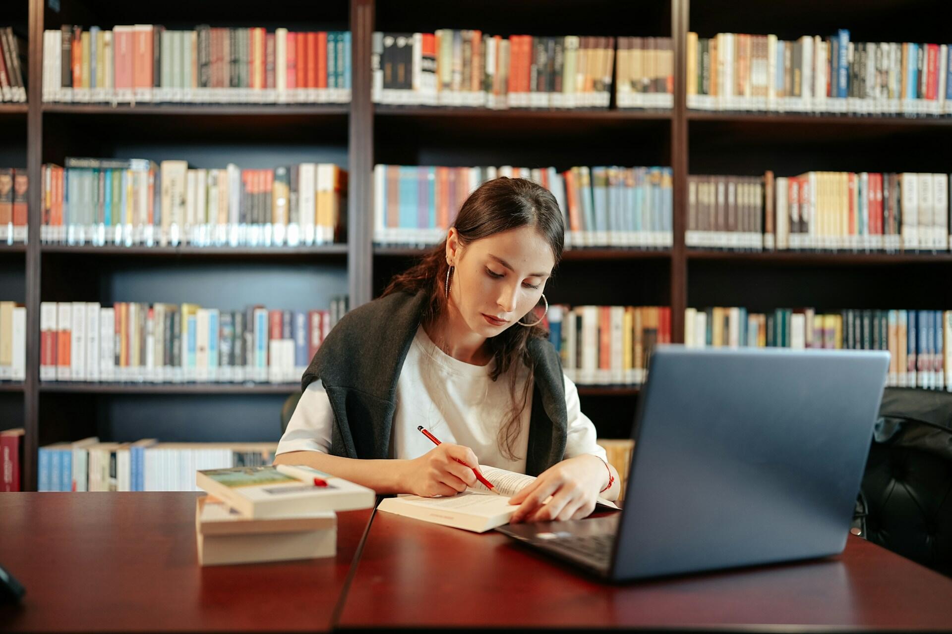 candidate using a computer and textbook to study and take notes