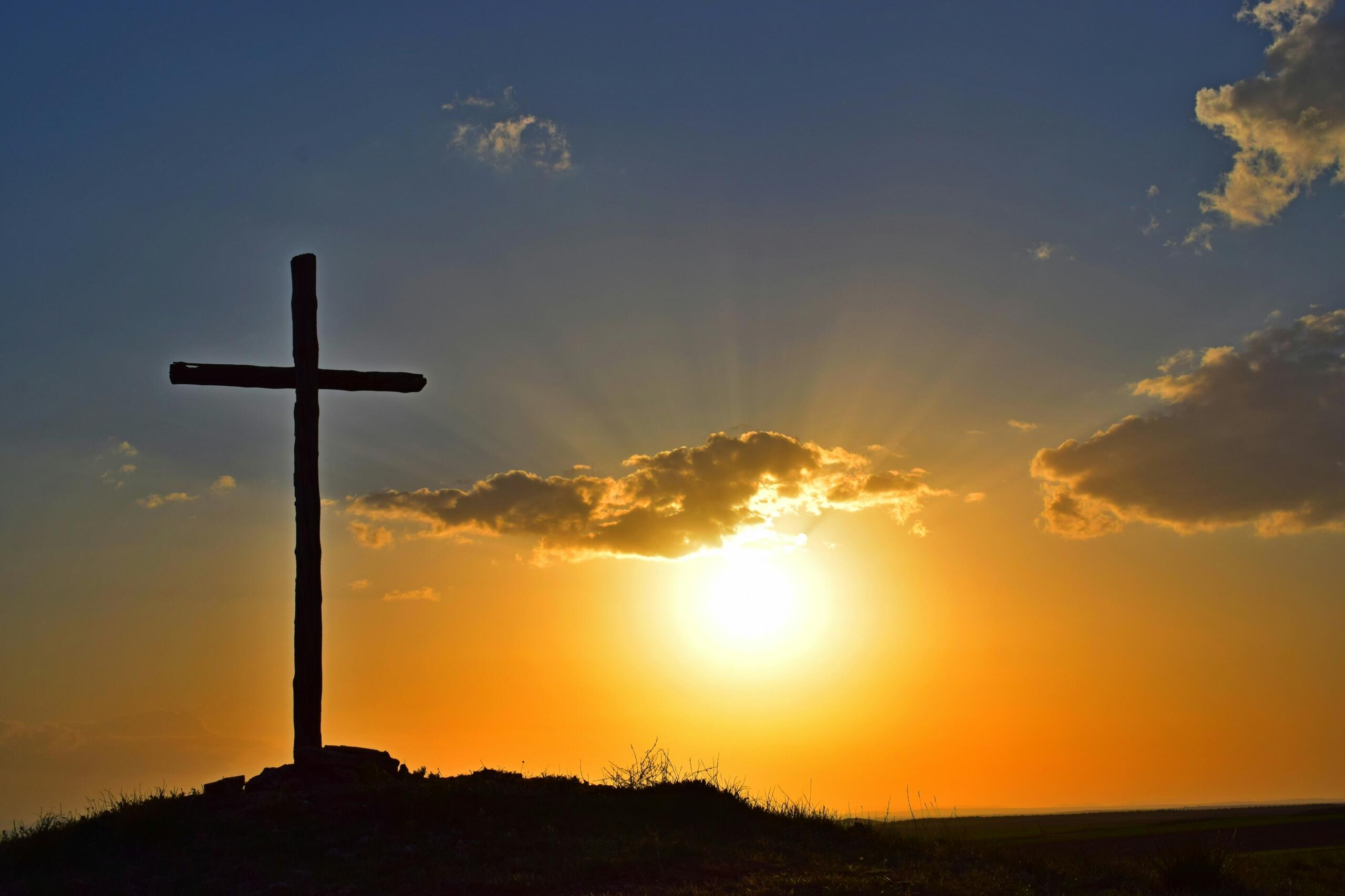 A cross with a sunset in the background.