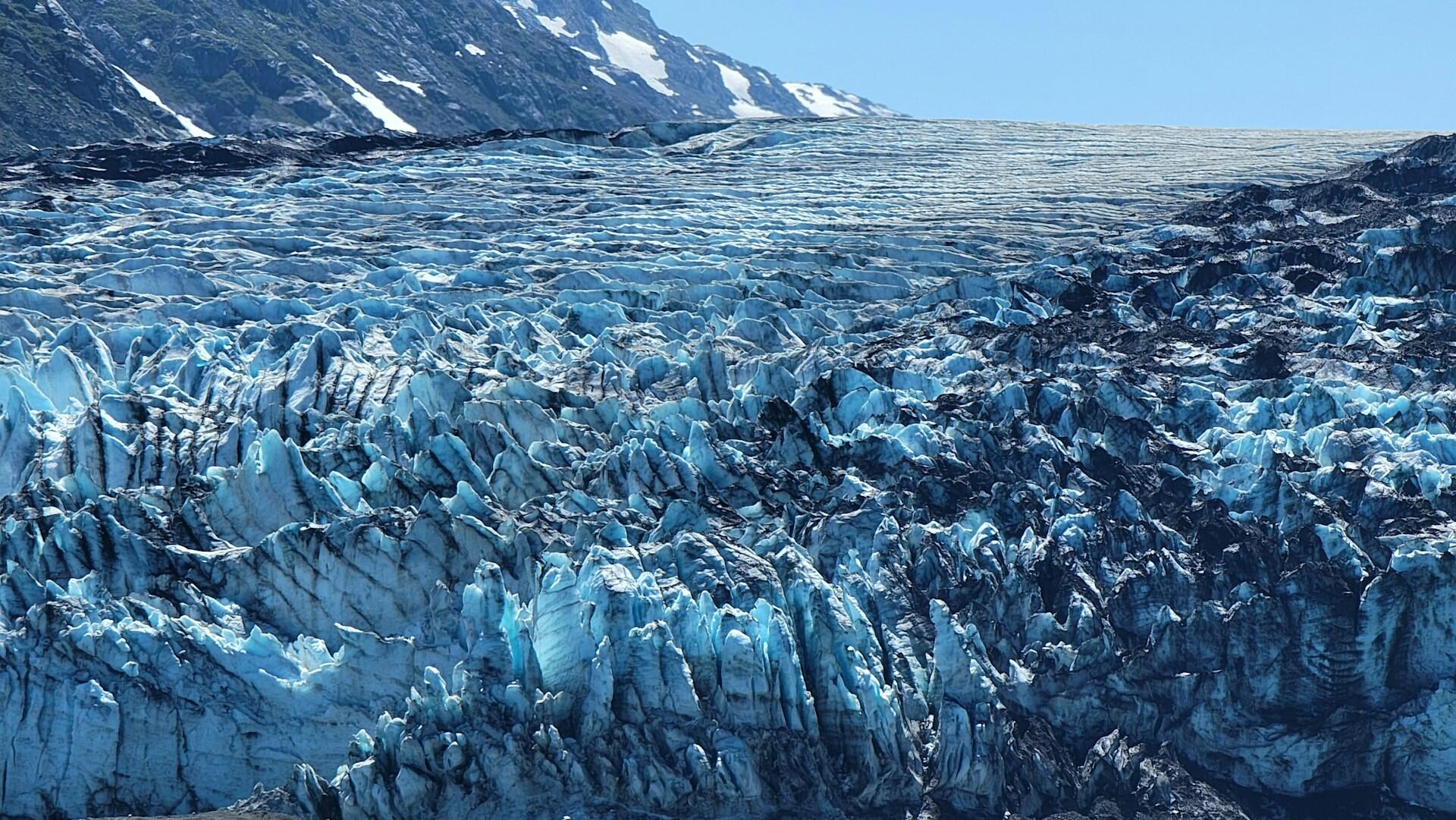 Aquamarine-colored ice crystals with stripes of black sediment make up a glacier at Glacier Park