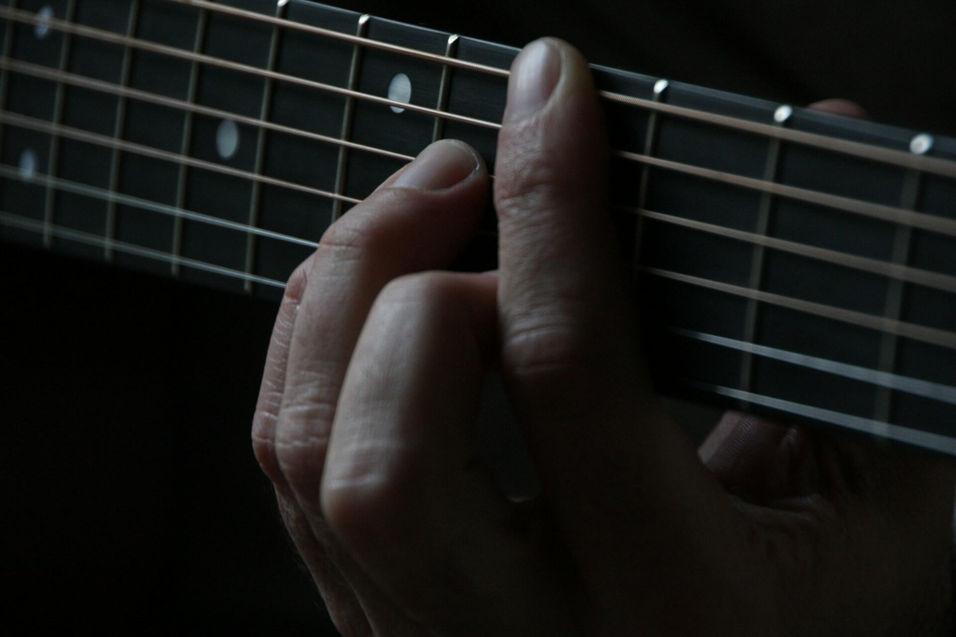 A black and white close up of someone playing on the guitar.