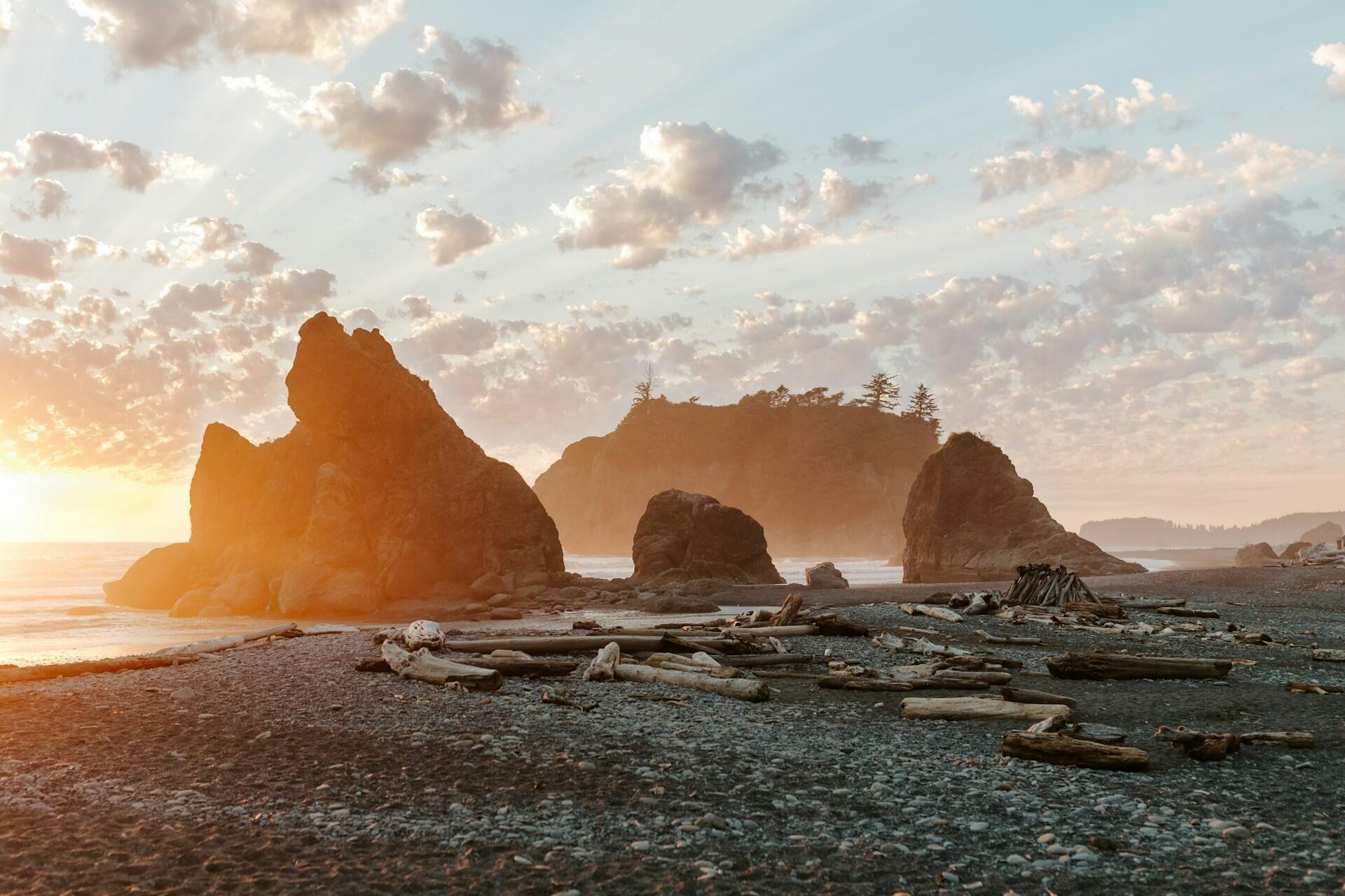 Rocky Beach with large rock protrusions and a rocky island in the background, with sunset rays making all the rocks appear to glow