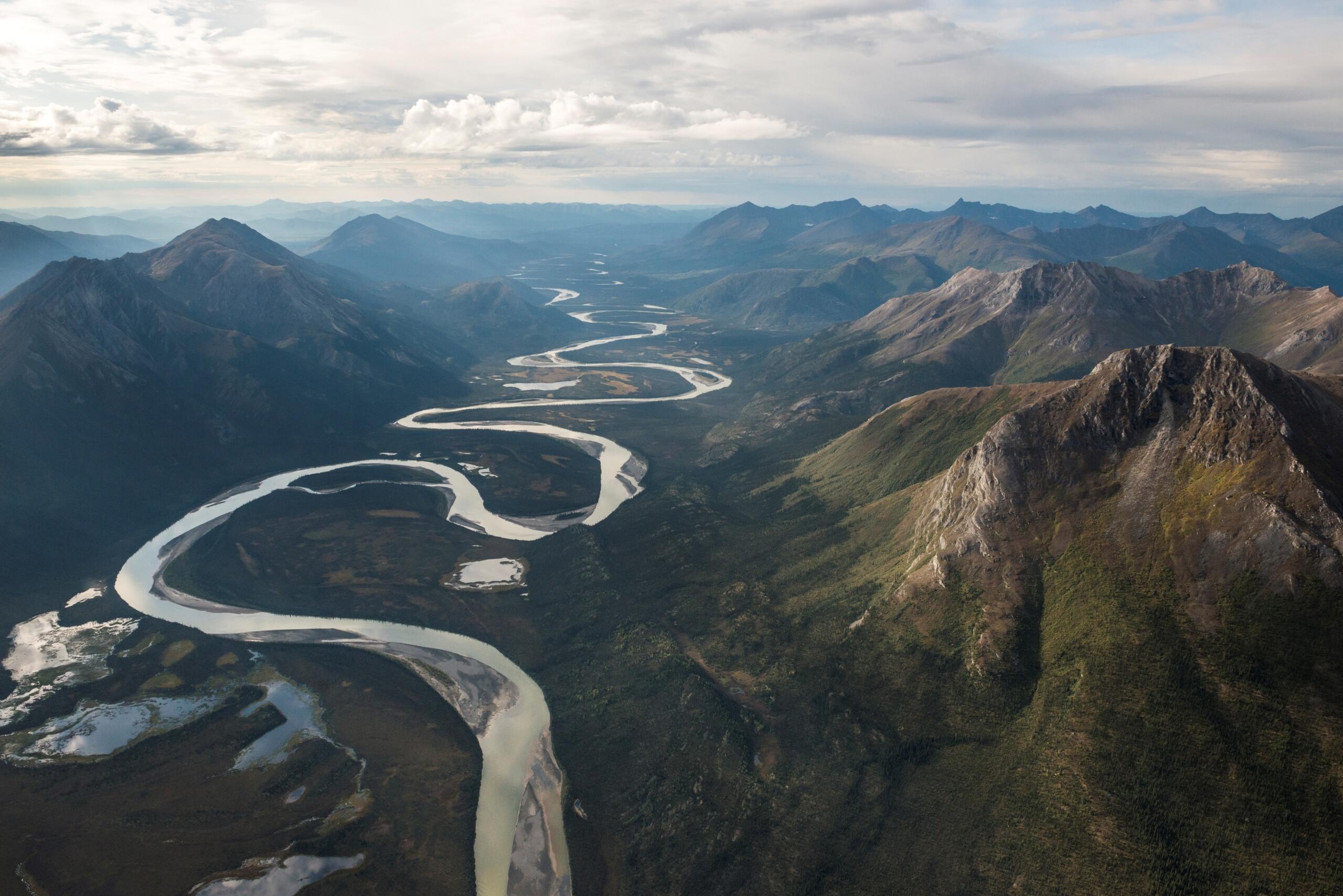 aerial view of a valley between two mountain ranges, with a thin, snaking River at the bottom of the valley