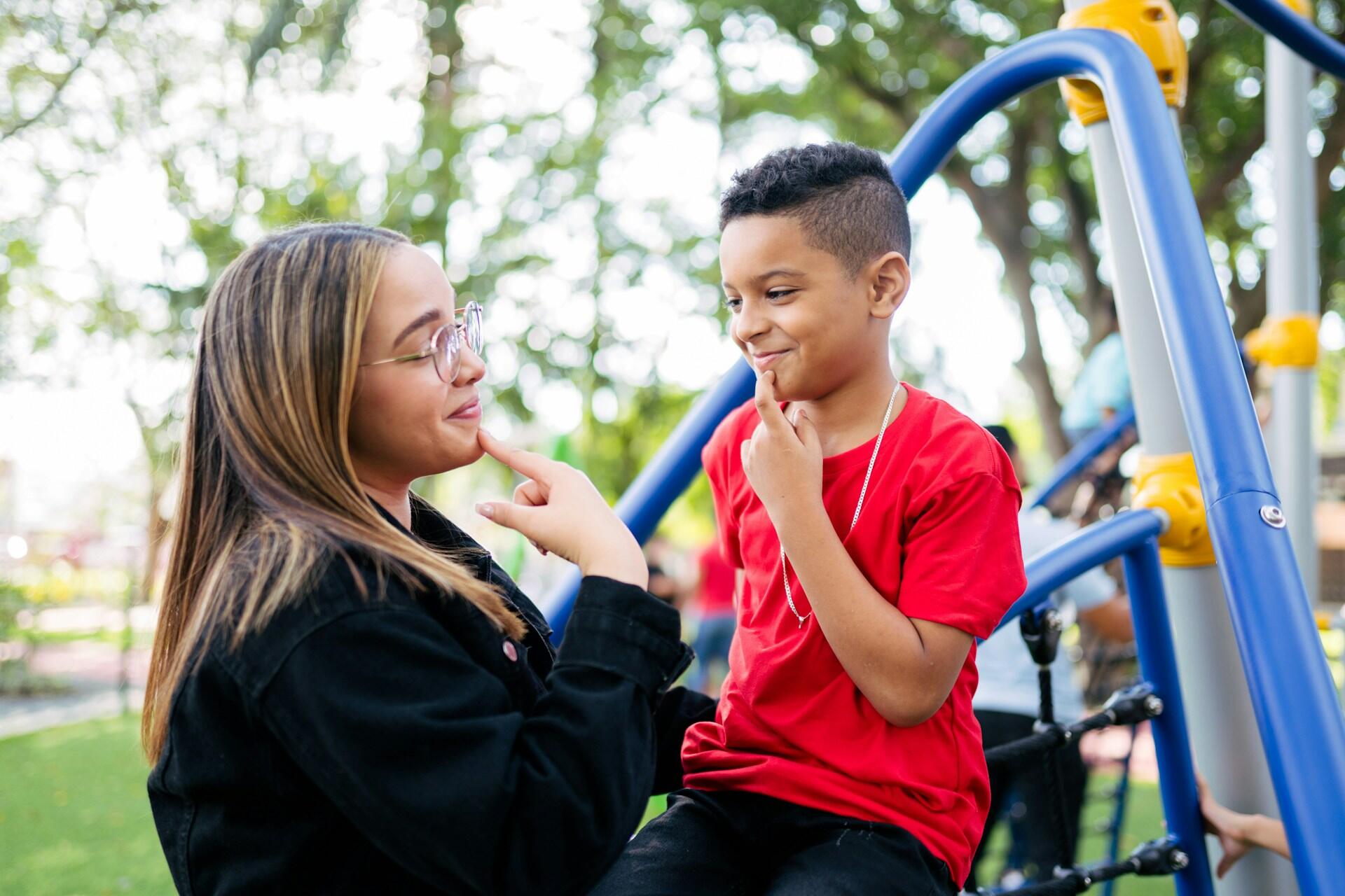 A sign language instructor showing a young boy a sign.